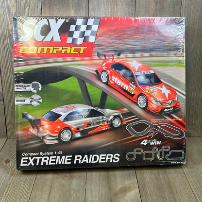 SCX Extreme Raiders 1:43 Scale Slot Car Set packaging featuring two sleek cars and race track layout.