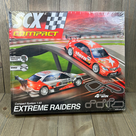 SCX Extreme Raiders 1:43 Scale Slot Car Set packaging featuring two sleek cars and race track layout.