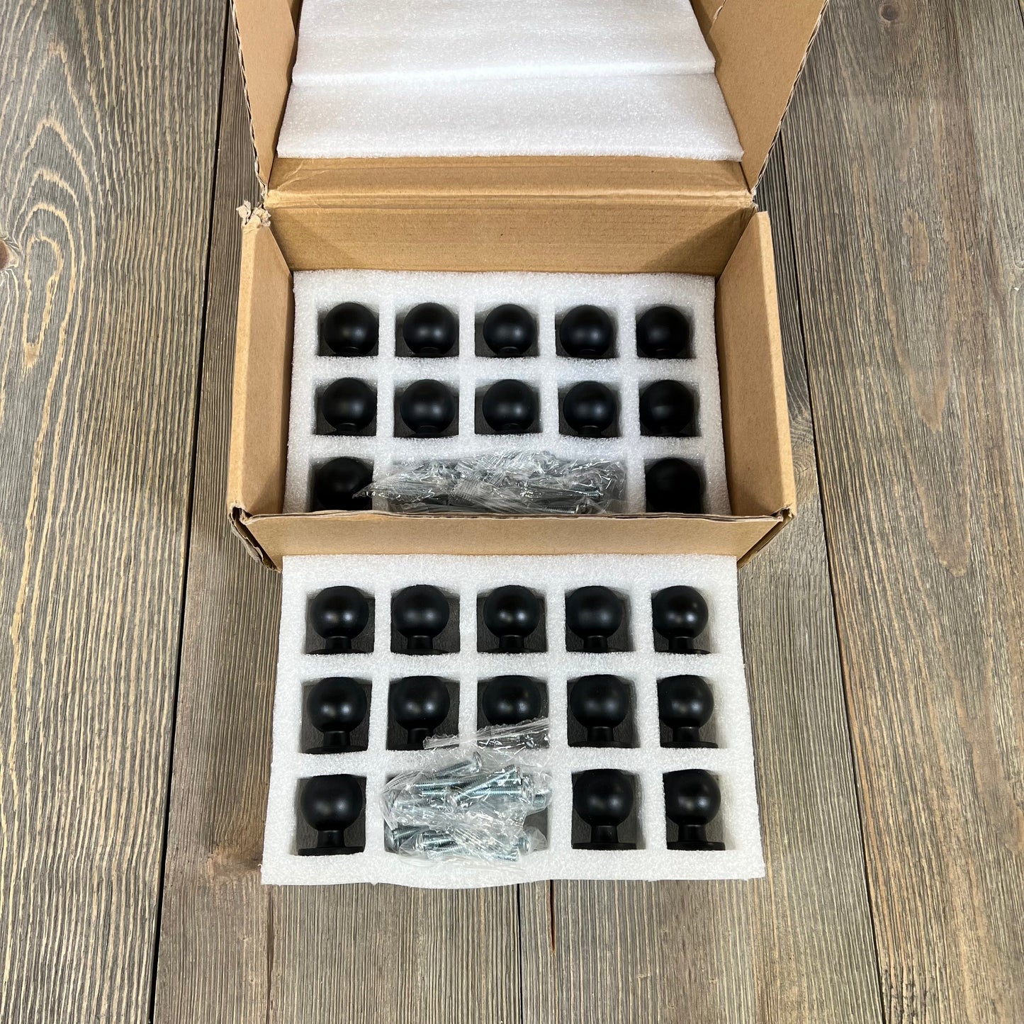 25-pack of matte black kitchen cabinet knobs in open box, showcasing sturdy drawer pulls for dresser drawers.