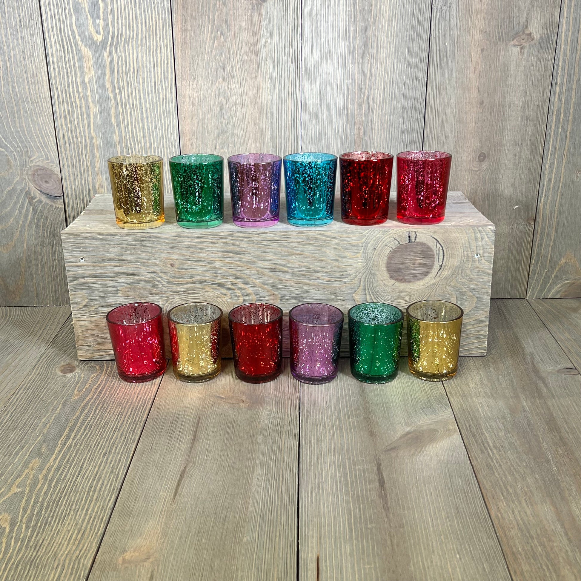 Assorted jewel tone mercury glass votive candle holders, set of 12, displaying deep rich colors on a wooden surface.