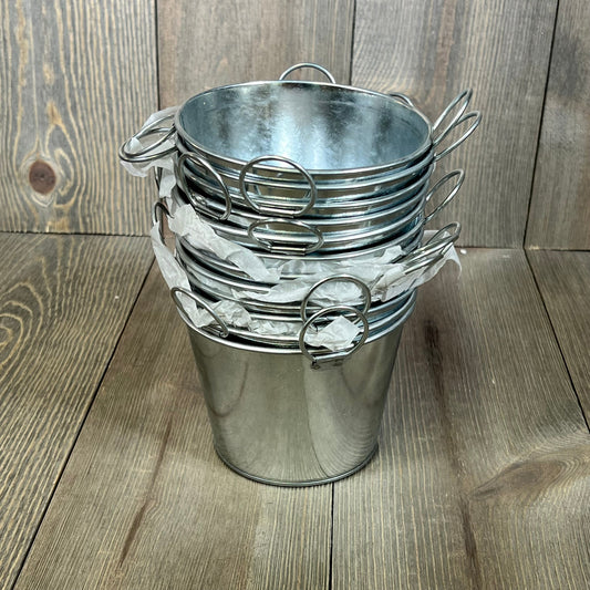 Stacked mini galvanized buckets with handles, perfect for parties and crafts, shown on a rustic wooden surface.