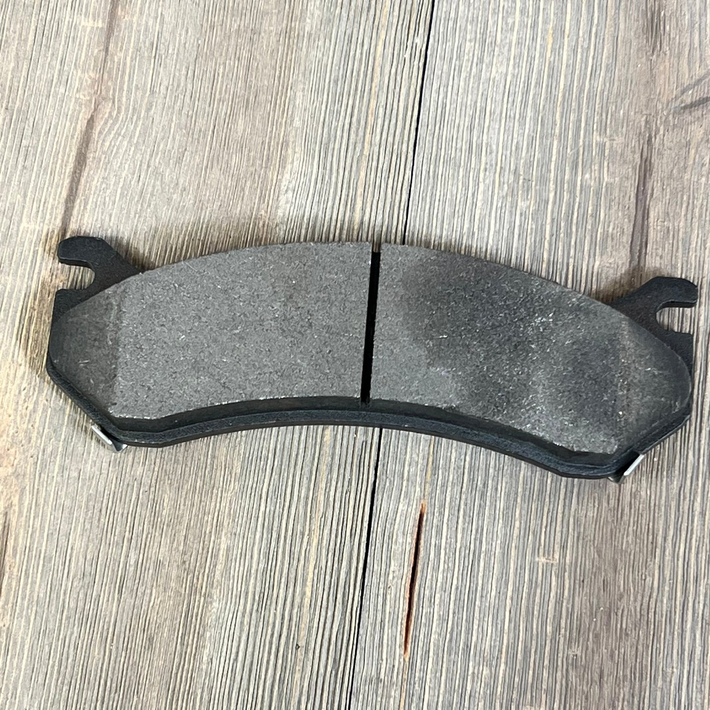 Ceramic brake pad for Chevrolet Suburban 2500, offering durability and performance on wooden surface.