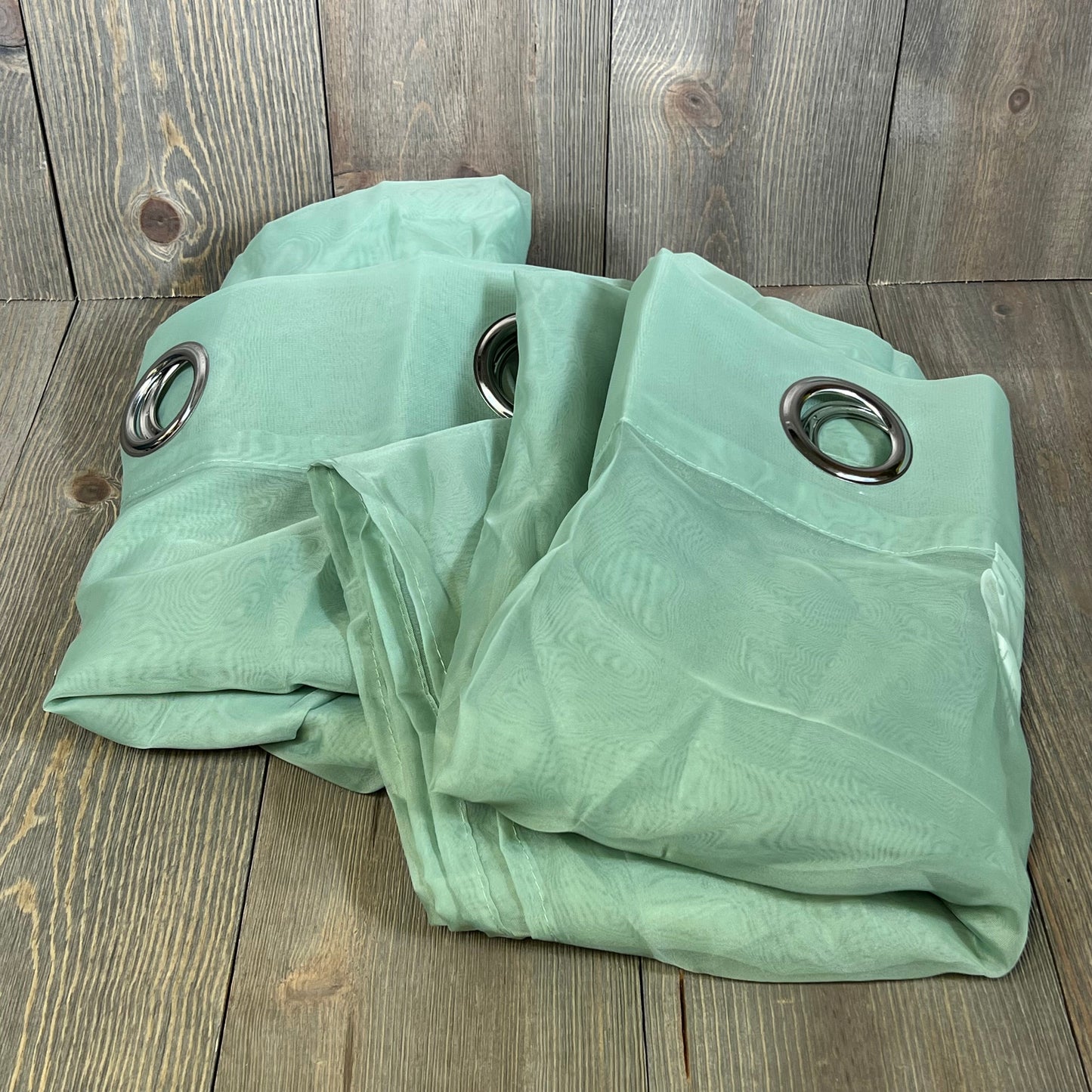Sage green sheer curtains with ring tops, perfect for farmhouse decor. Elegant voile texture, ideal for living rooms.