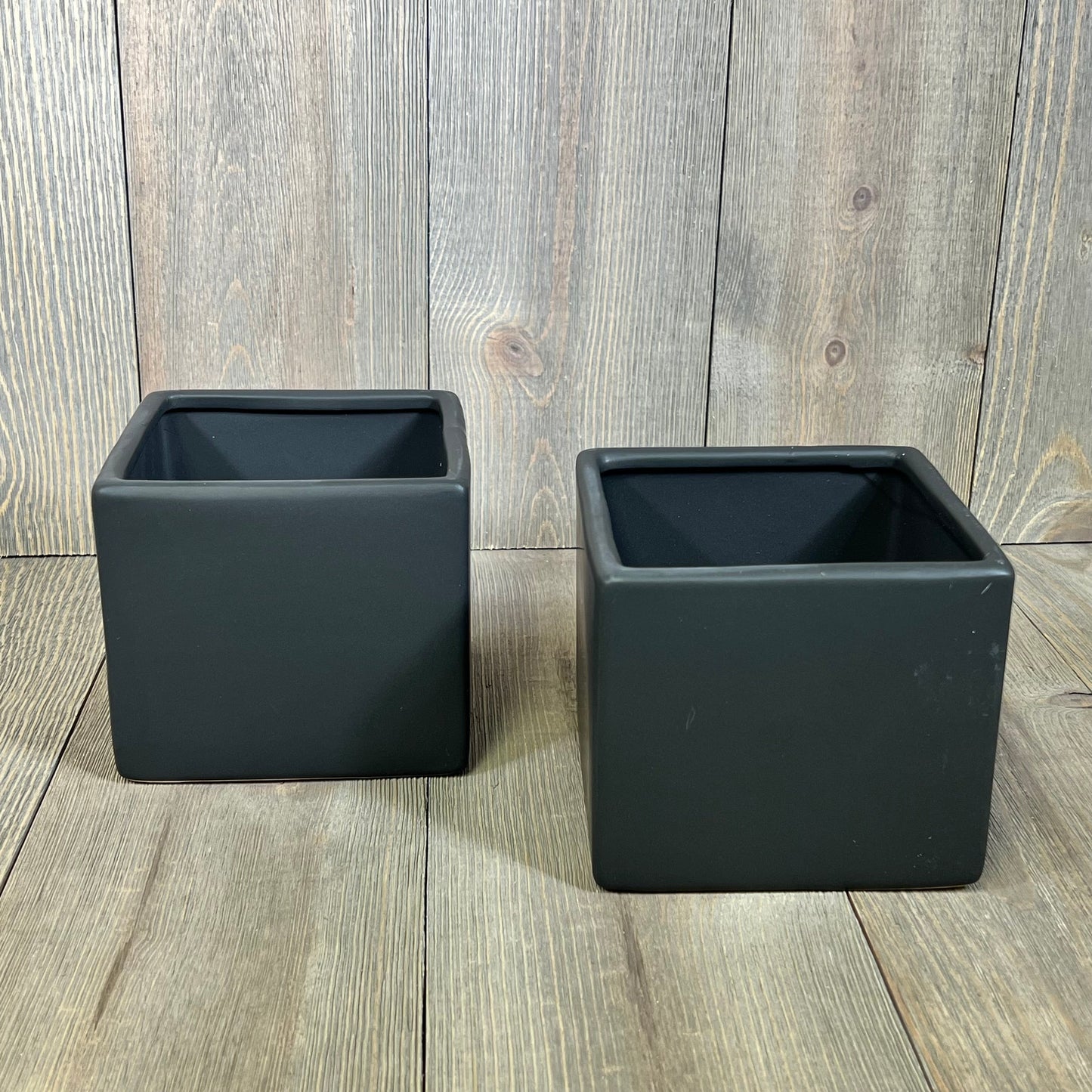 Modern black ceramic square plant pots, perfect for succulents, set of two on a wooden surface. Ideal for home decor.