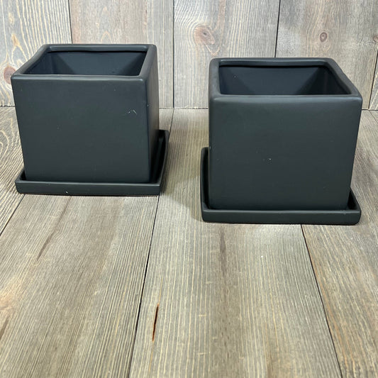 Modern black ceramic square plant pots set, perfect for small flowers or succulents, on a wooden background.