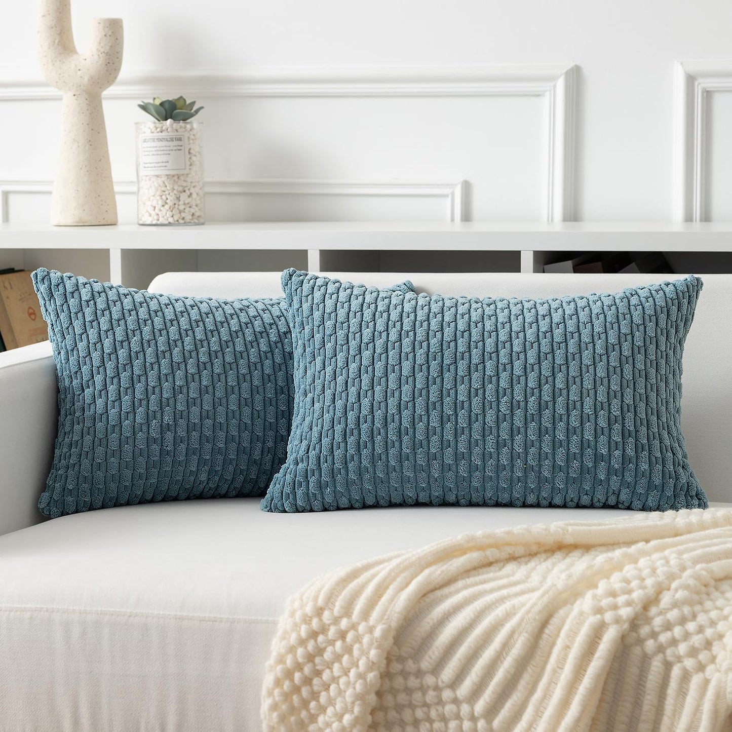 Soft corduroy throw pillow covers in blue-grey, adding a boho touch to a white sofa for cozy home decor.