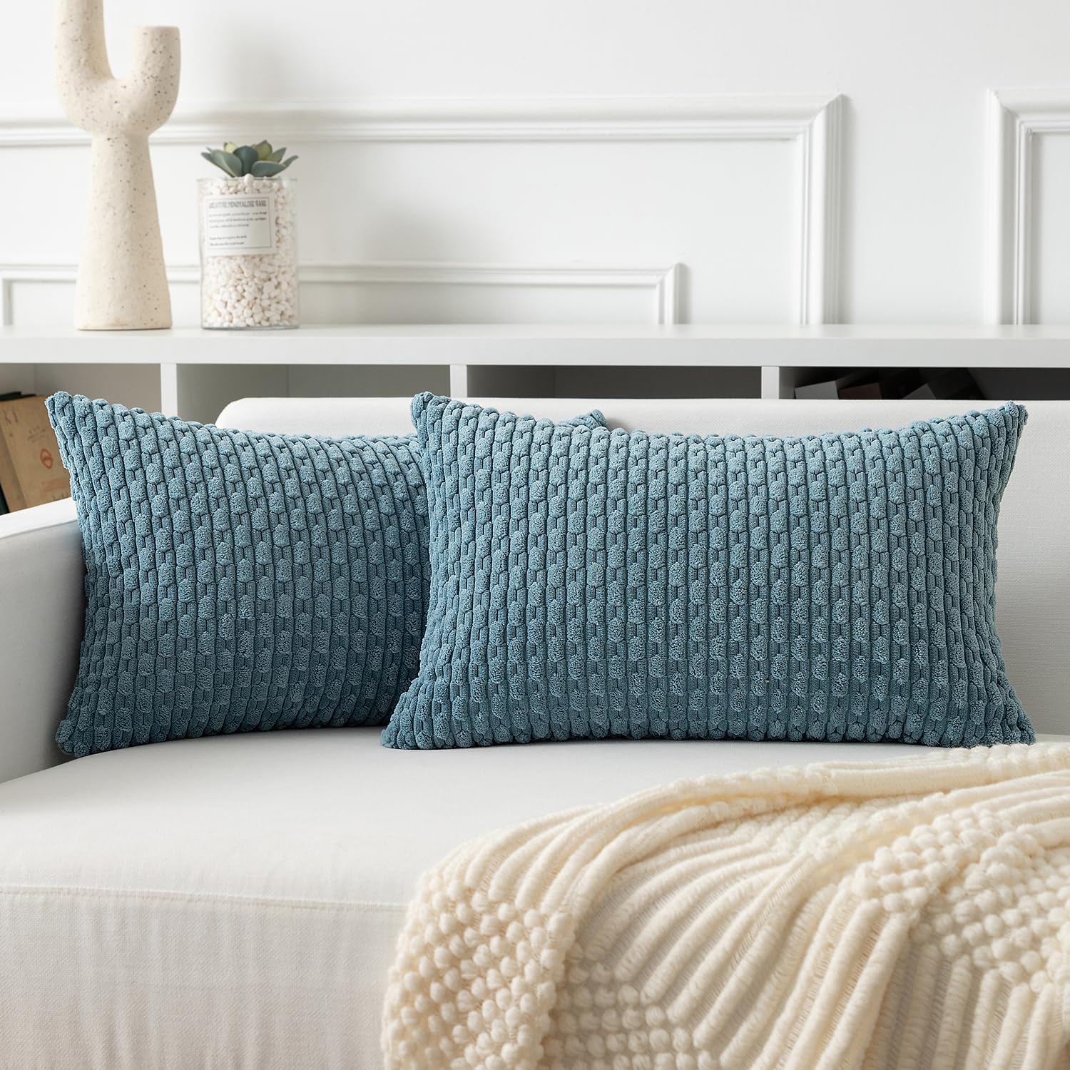Soft corduroy throw pillow covers in blue-grey, adding a boho touch to a white sofa for cozy home decor.