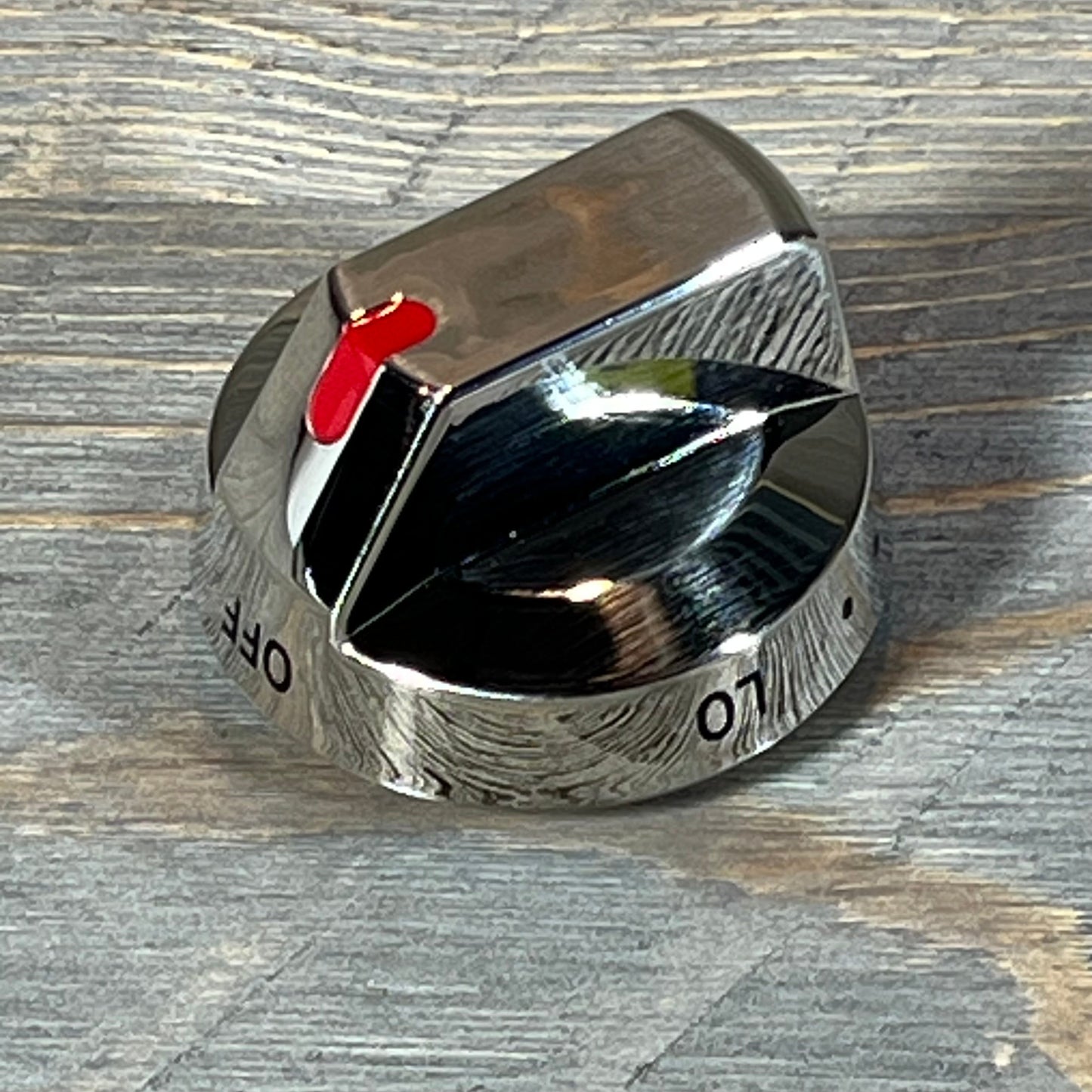 Shiny Samsung gas stove burner control knob with red indicator on textured surface.