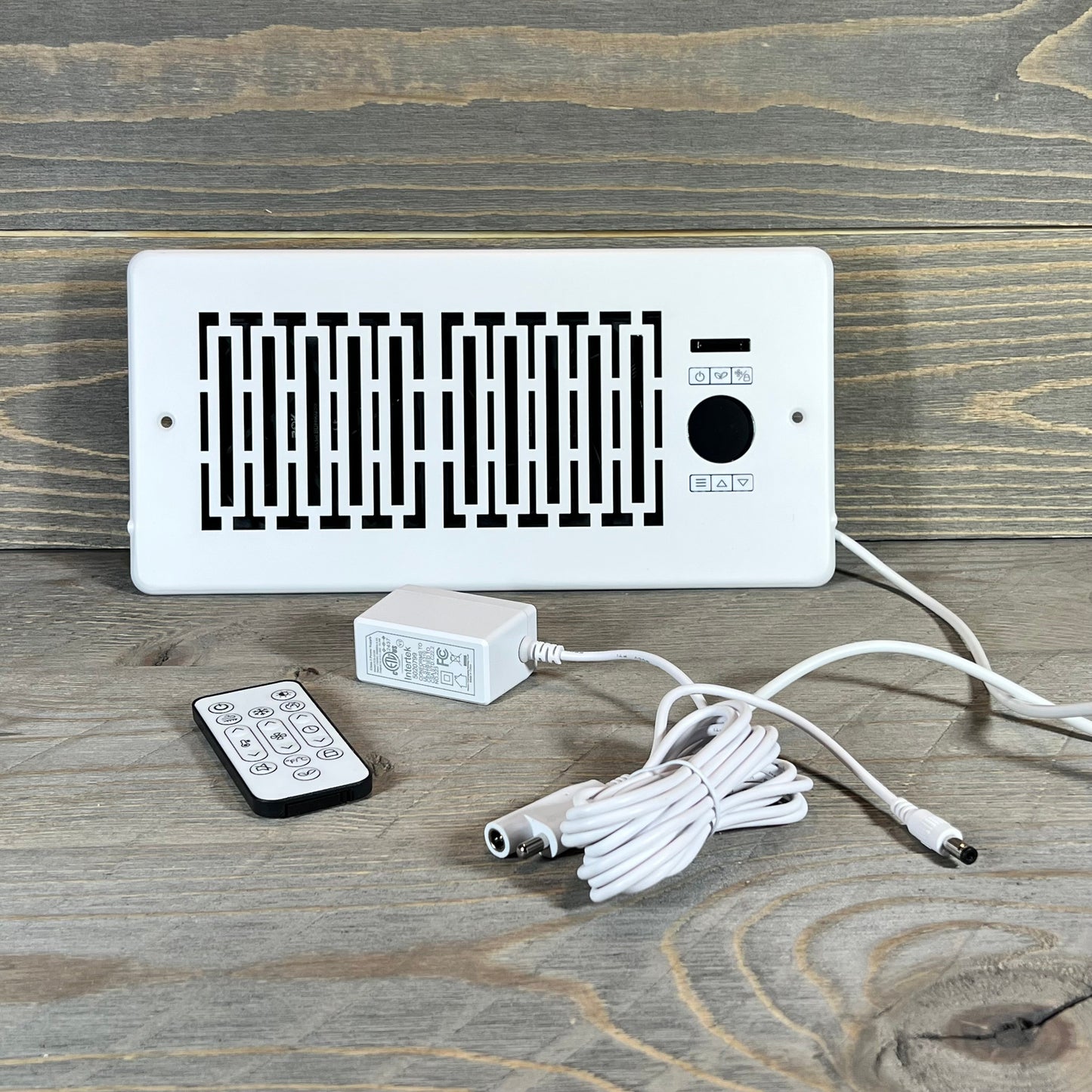 Smart Register Booster Fan with remote, cable, and adapter displayed on a wooden surface for 4" x 10" vents.