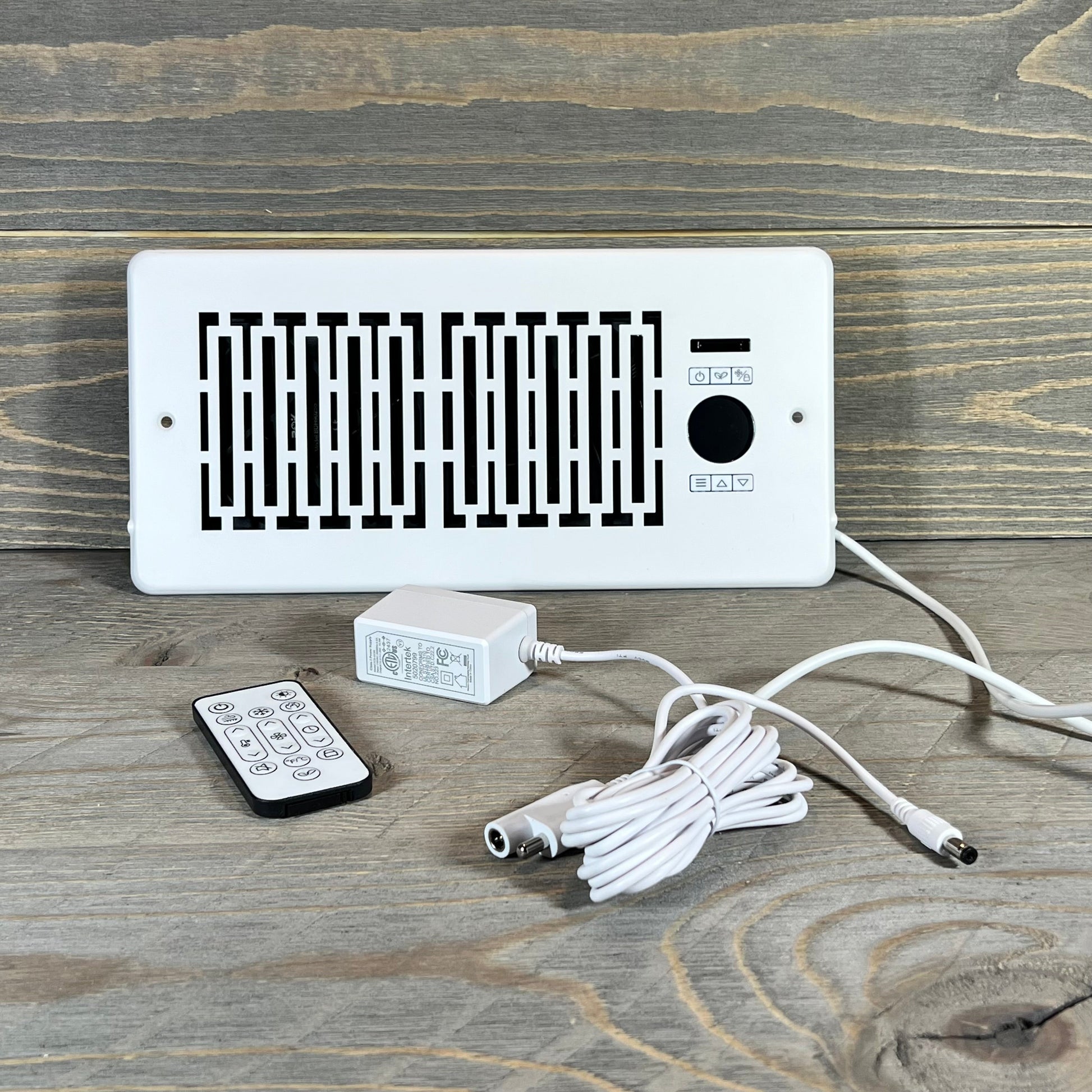 Smart Register Booster Fan with remote, cable, and adapter displayed on a wooden surface for 4" x 10" vents.
