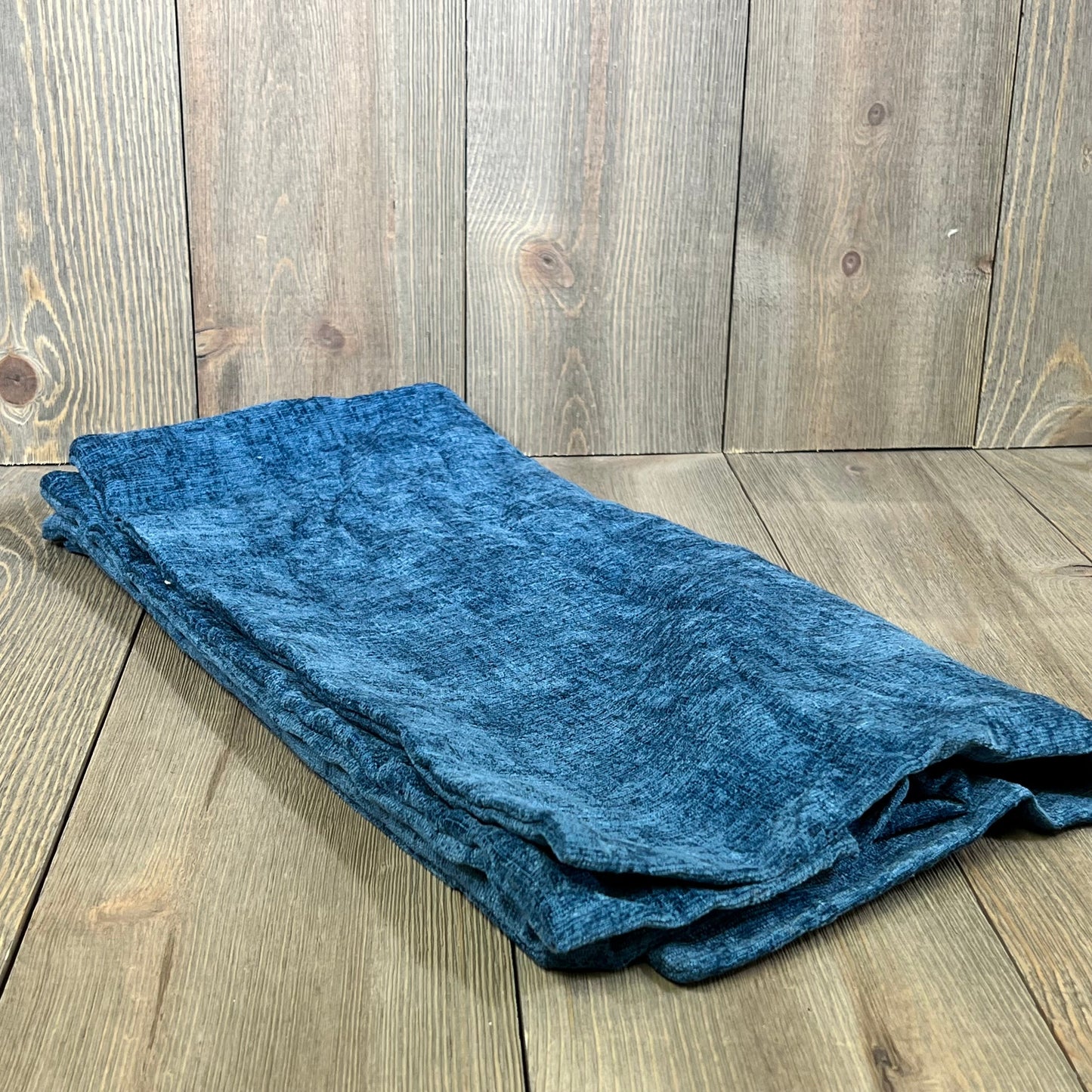 Soft blue chenille throw pillow covers folded on wooden surface, perfect for sofa or couch decor.