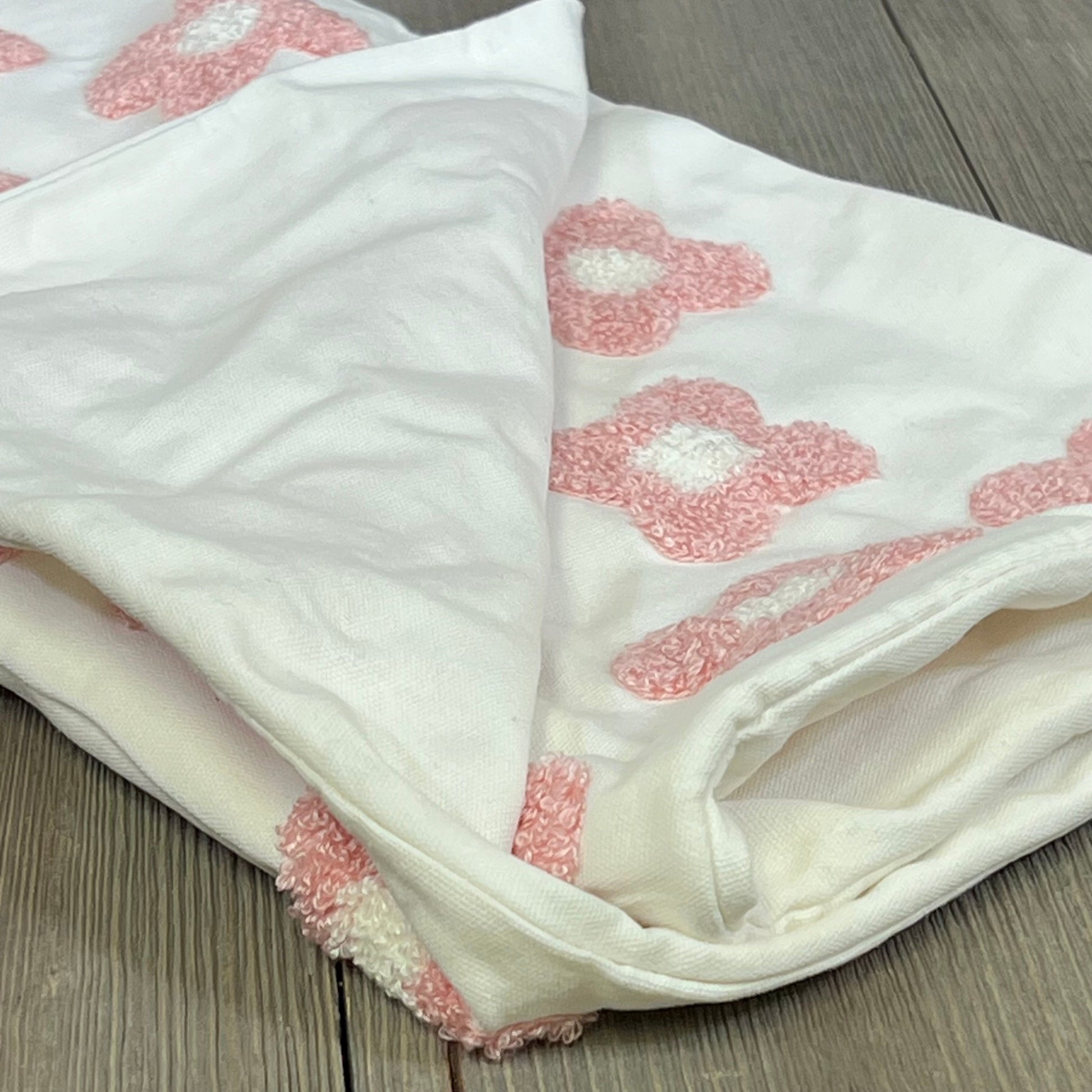 Pink and white daisy sun flower jacquard pillow cover, folded on a wooden surface, perfect for couches and beds.