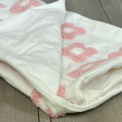 Pink and white daisy sun flower jacquard pillow cover, folded on a wooden surface, perfect for couches and beds.