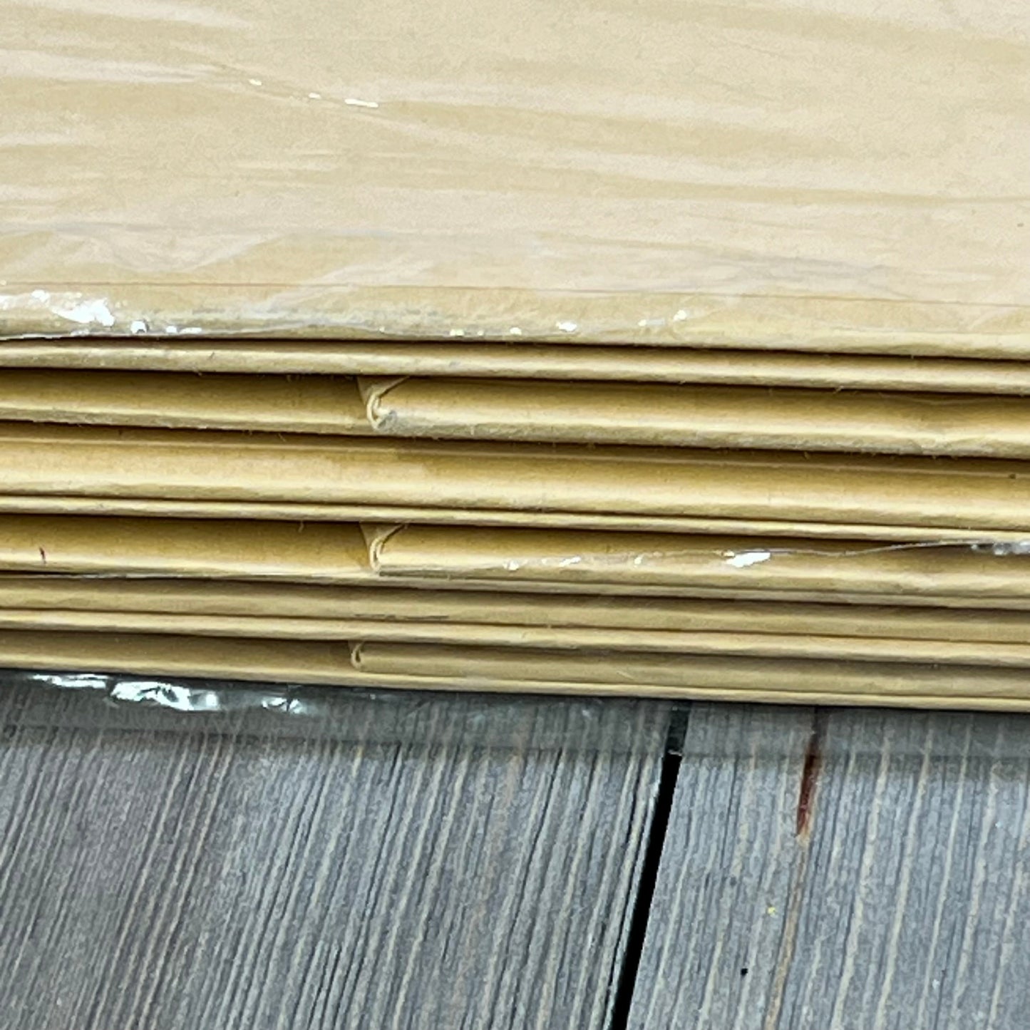 Stack of flat PACKHOME large kraft gift boxes, showcasing sturdy collapsible design with magnetic closure, on wood surface.
