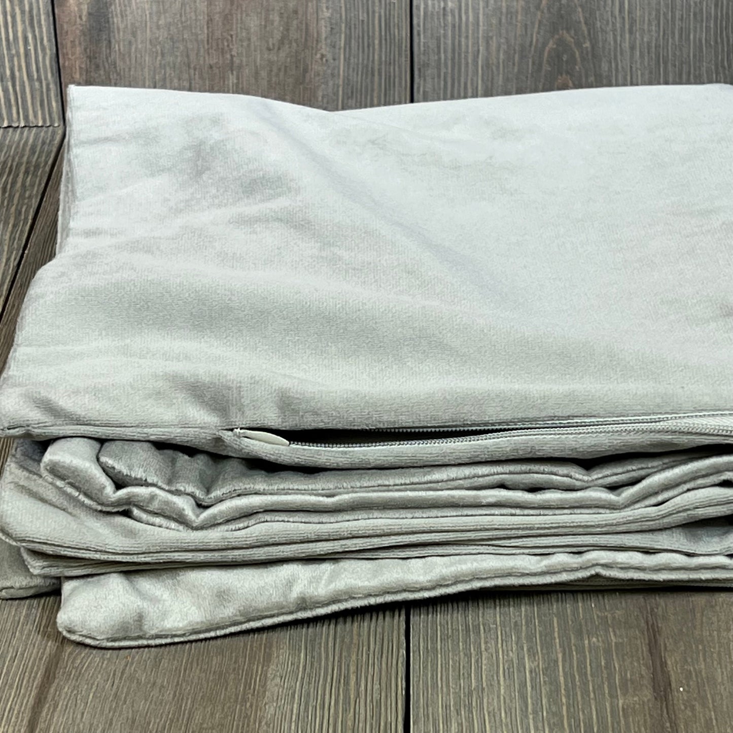 Cozy light-grey velvet pillow cases in 22x22 size, perfect for farmhouse decor, neatly folded on a wooden surface.