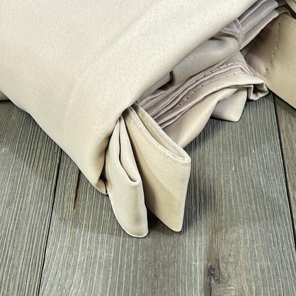 Beige waterproof outdoor curtains folded on wooden surface, ideal for patios, providing privacy and blackout features.