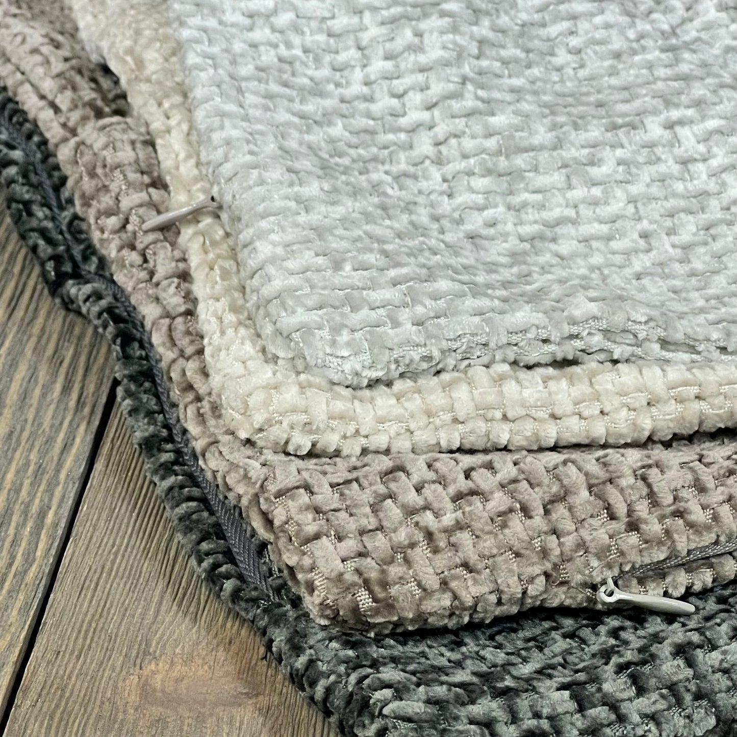 Neutral chenille pillow covers in gray tones, perfect for farmhouse or boho decor, shown stacked on a wooden surface.