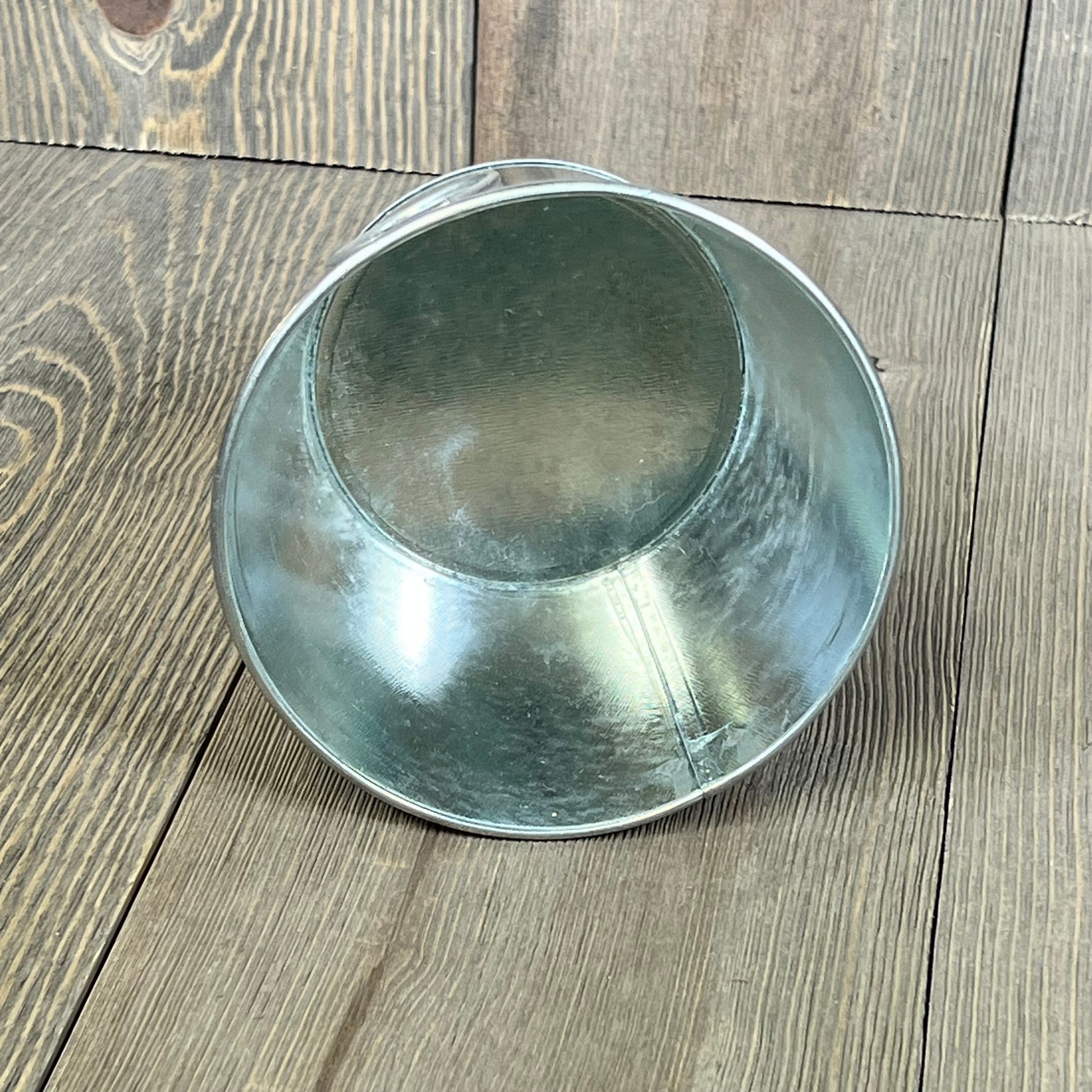 Mini galvanized bucket with handle on rustic wooden floor, 4.5 x 3.5 inches, ideal for home decor or gardening.