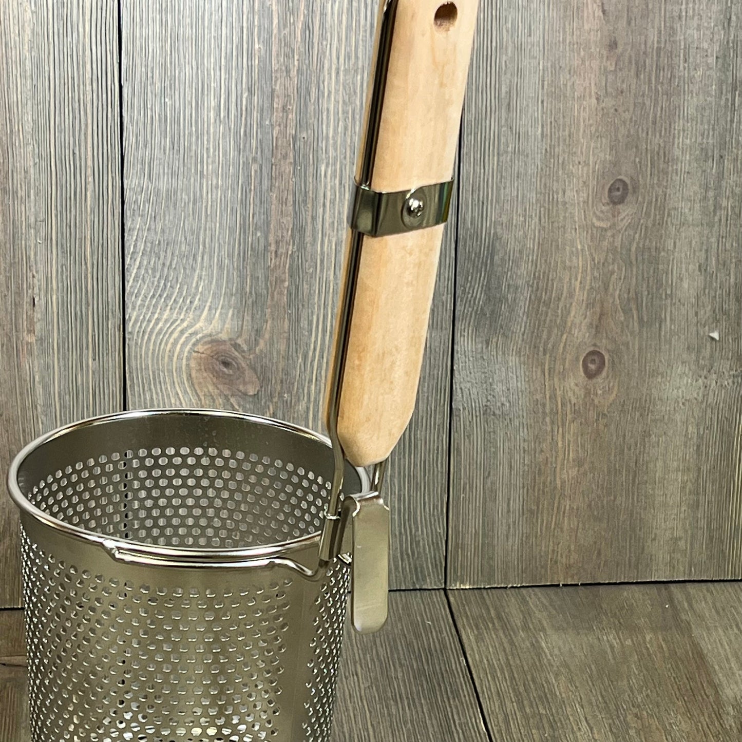 Stainless steel pasta cooker basket with a wooden handle, perfect for straining noodles and dumplings in the kitchen.