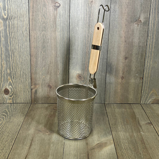Stainless steel pasta cooker basket with a wood handle, ideal for straining noodles and dumplings, on a wooden surface.