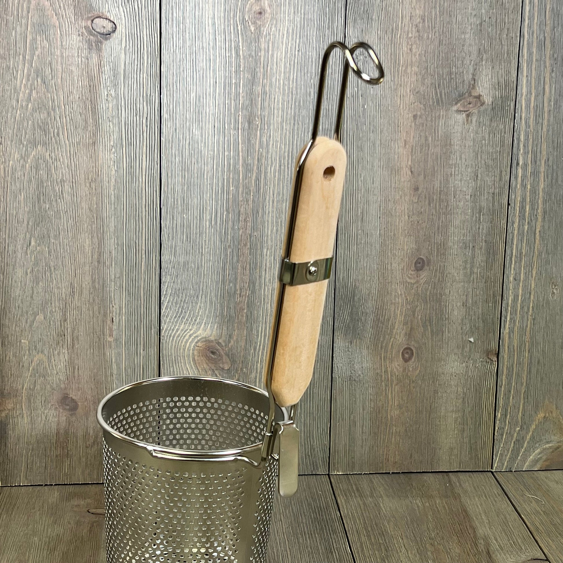 Stainless steel pasta cooker basket with a wooden handle, ideal for straining noodles and dumplings in the kitchen.