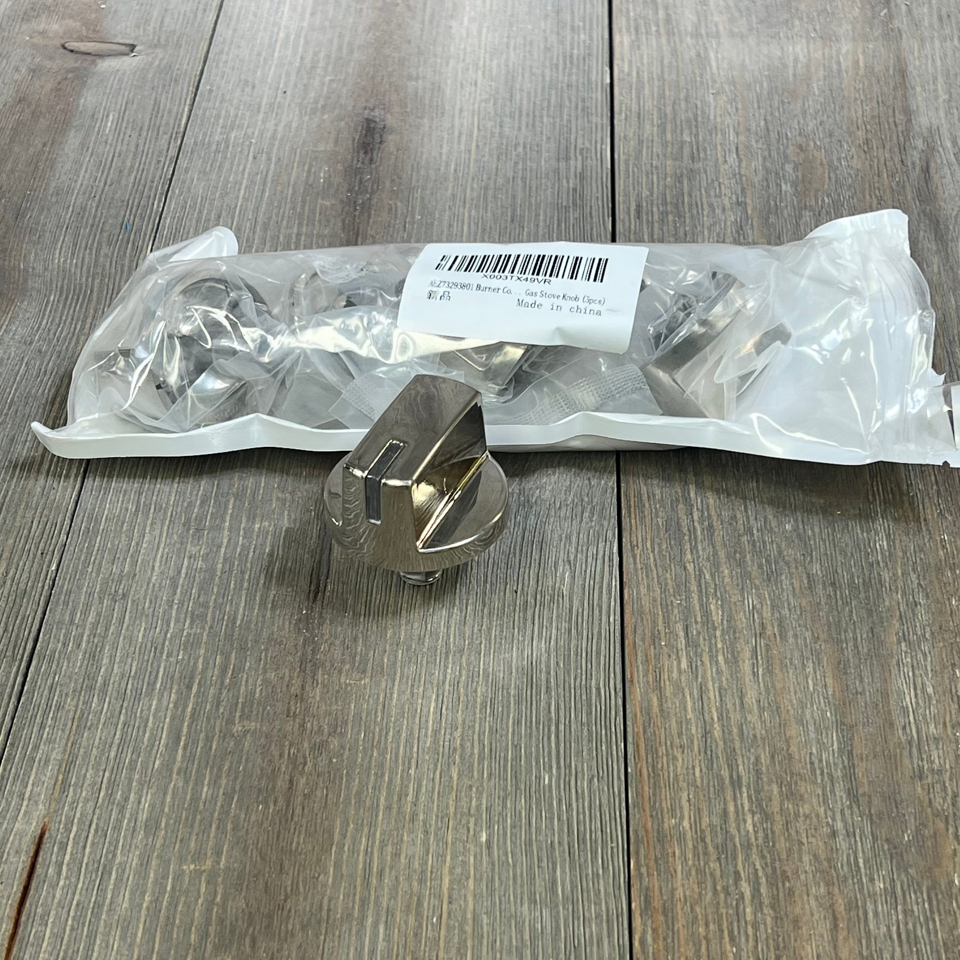 Stainless steel burner control dial for LG range stove, shown with packaging on a wooden surface.