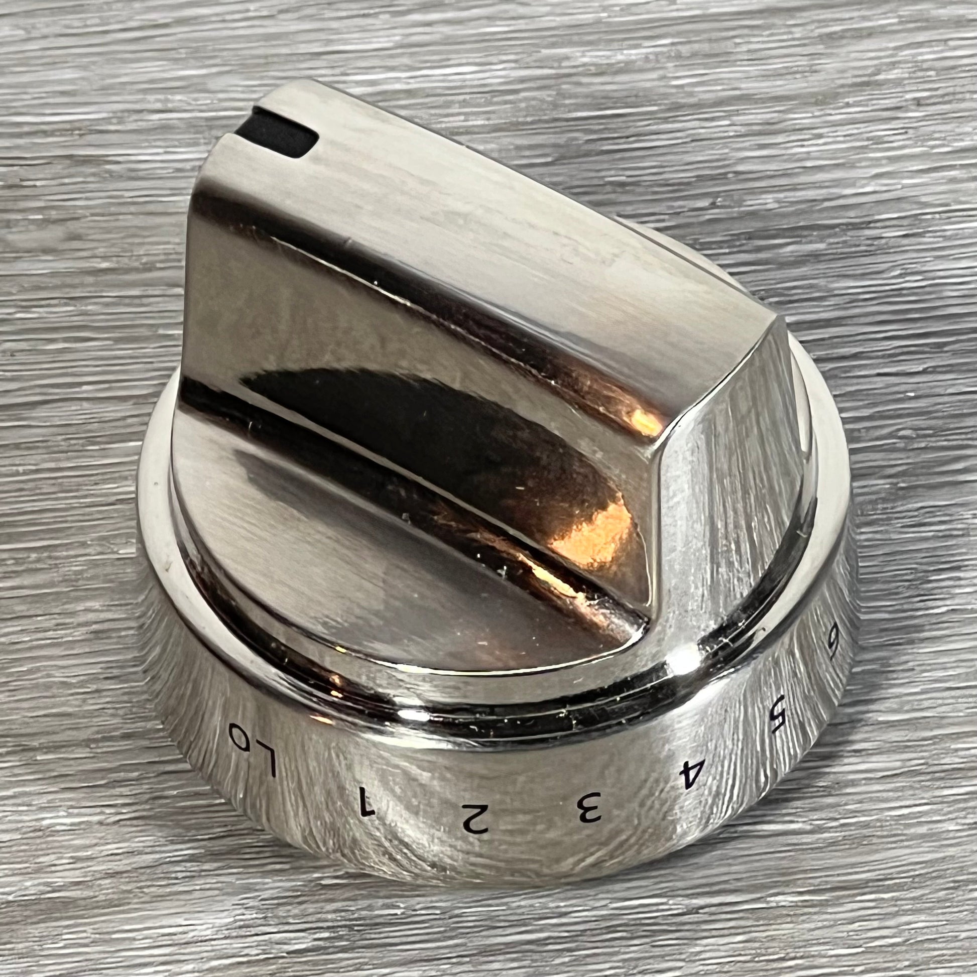 Stainless steel GE stove knob replacement on a textured surface, showing clear number markings for easy adjustment.