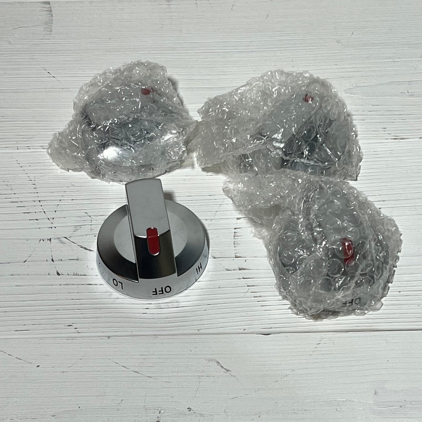 Four Samsung stove knob replacements, model DG94-03500A/Z, with shiny finish and red indicators, partially wrapped in bubble wrap.