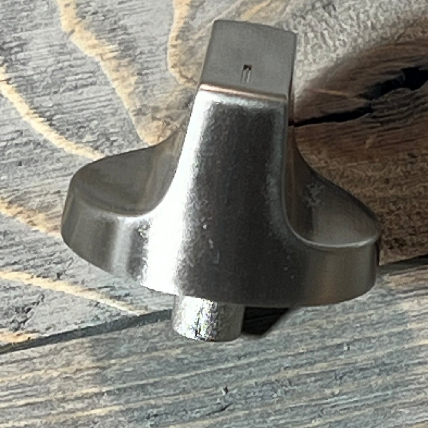 Stainless steel Whirlpool gas range knob replacement shown on a rustic wooden surface.