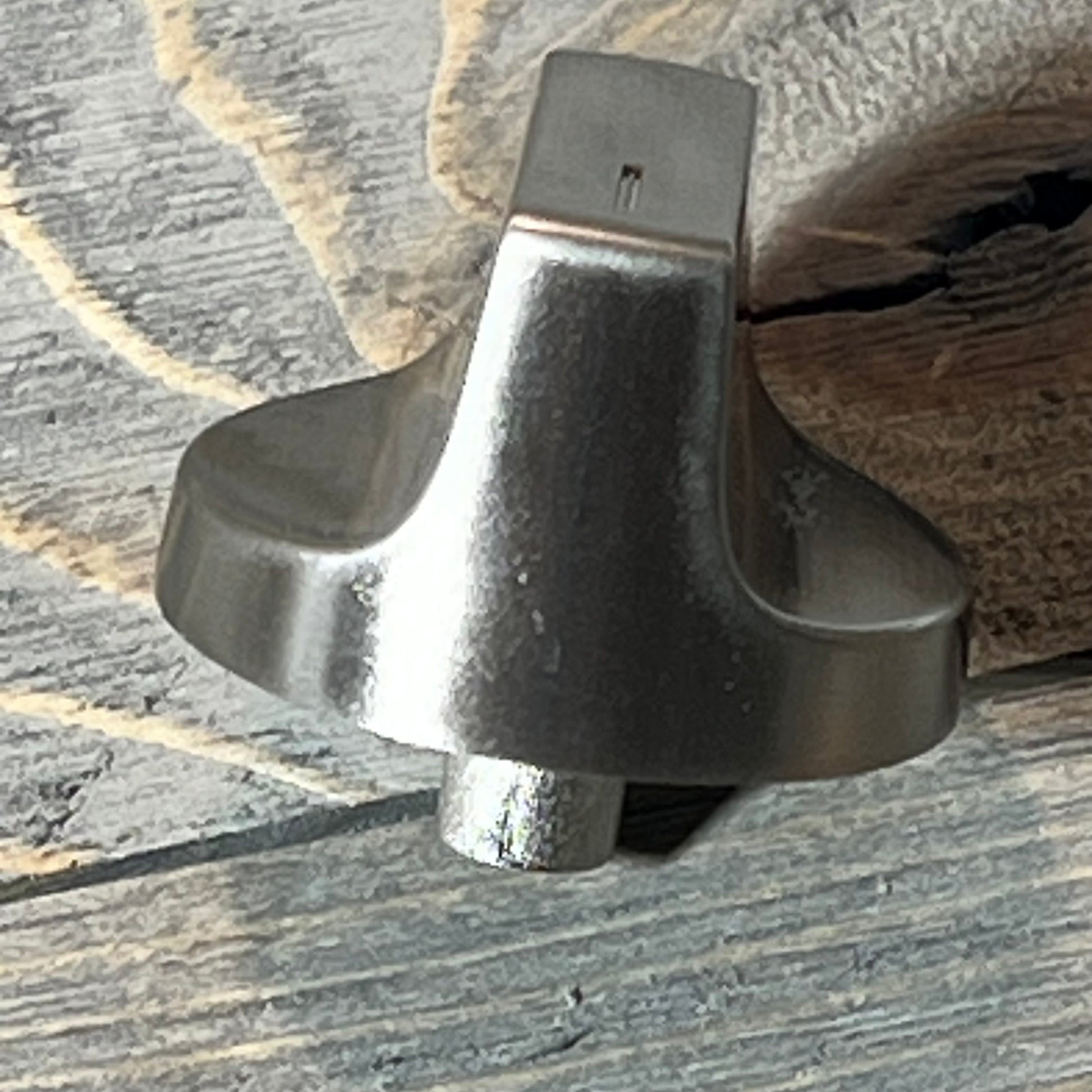 Stainless steel Whirlpool gas range knob replacement shown on a rustic wooden surface.