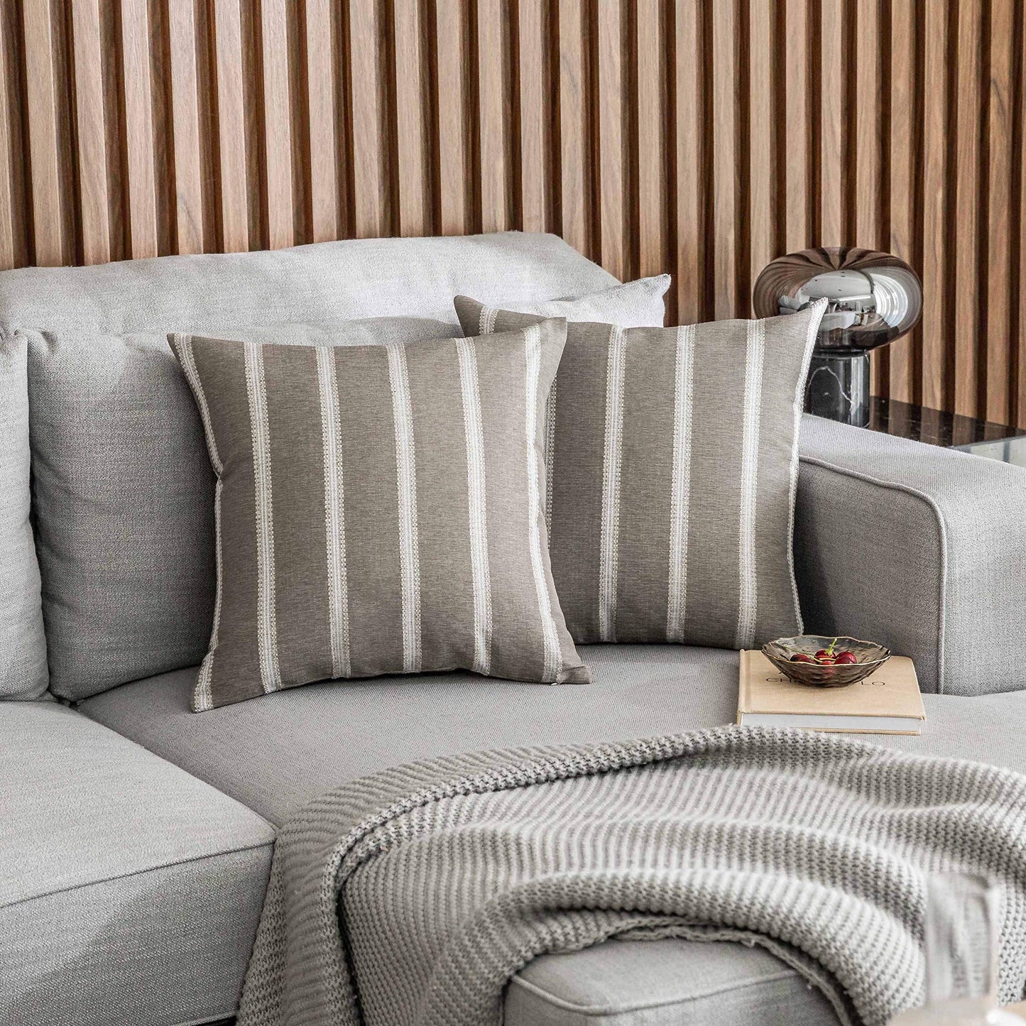 Tan stripe decorative pillow covers on a modern grey sofa, 24x24 inches, perfect for living room decor. Set of 2 Euro shams.
