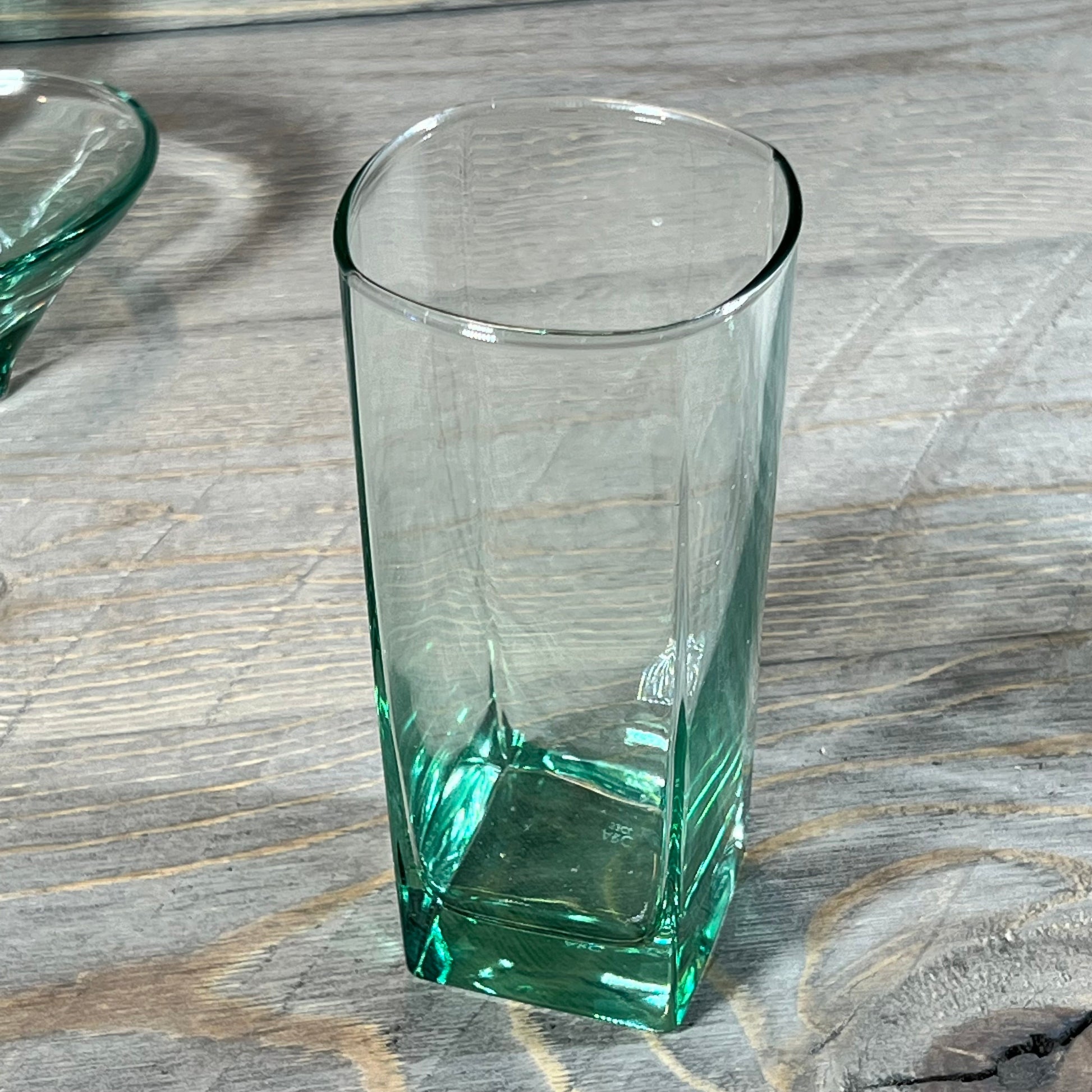 Tall green teal glass tumbler from the 5-piece bathroom accessory set on wooden surface.