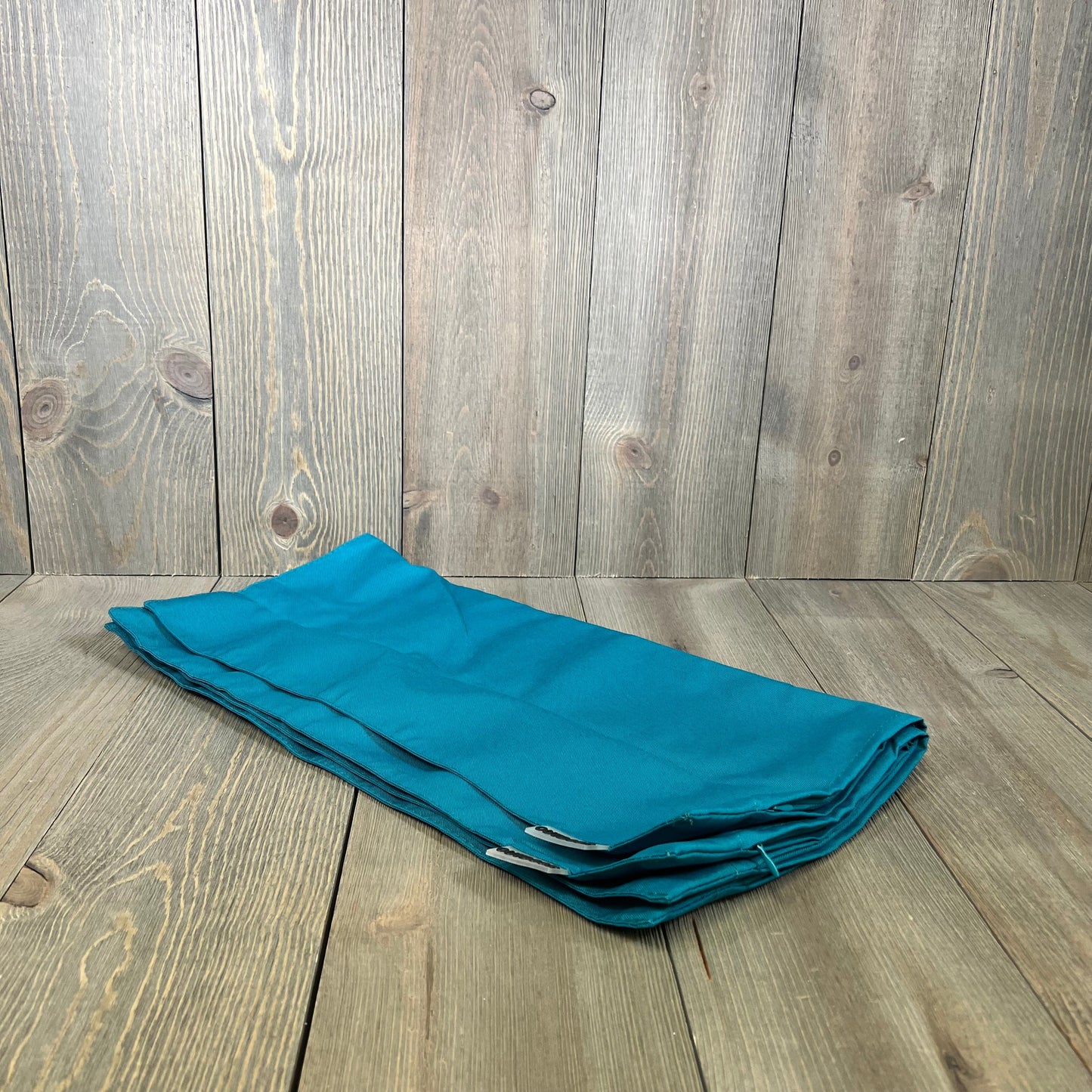 Teal blue waterproof pillow covers on wooden background, ideal for outdoor patio decor and garden cushions, 18x18 inches.