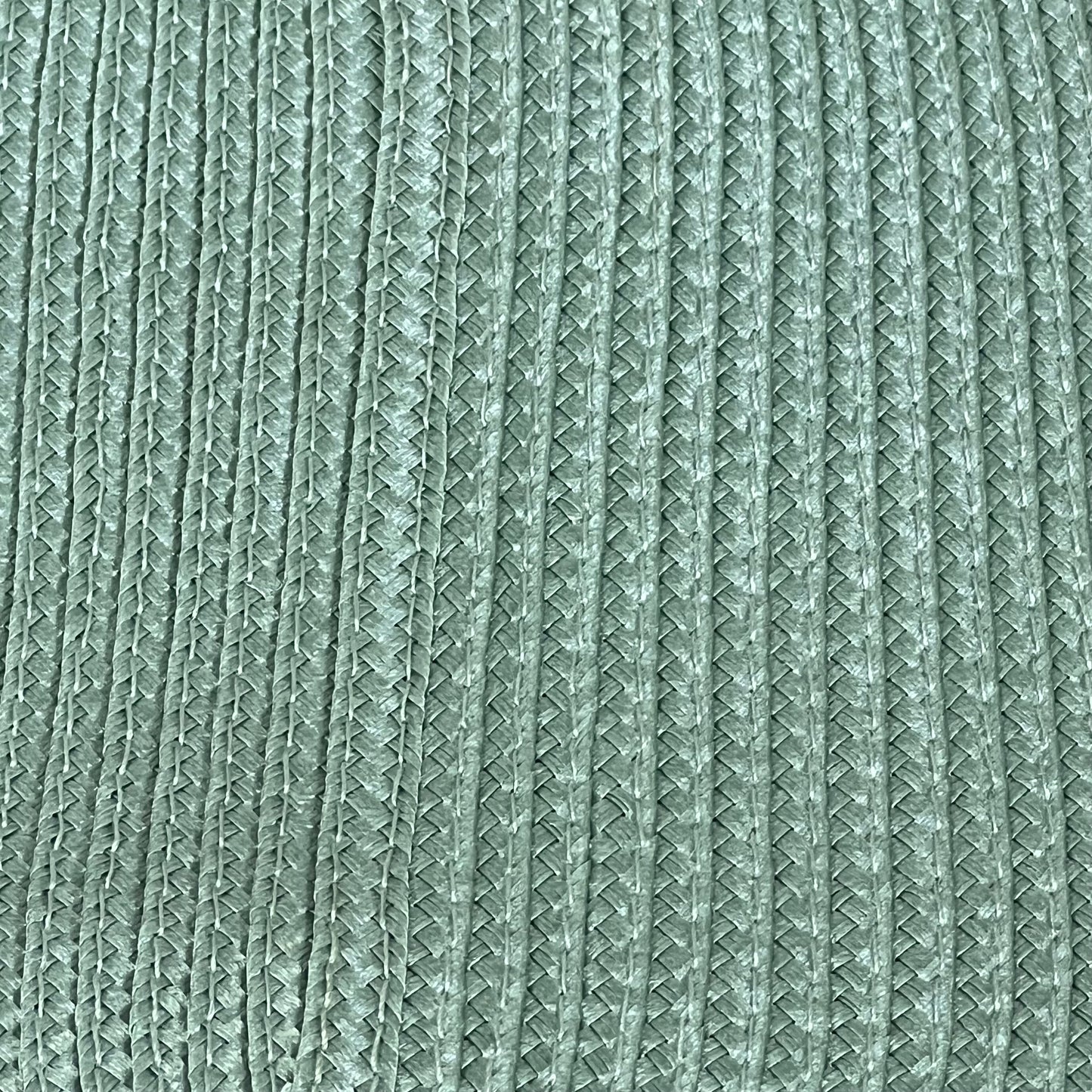 Sage green woven vinyl placemat with textured design, non-slip and heat-resistant for dining table, easy to clean.