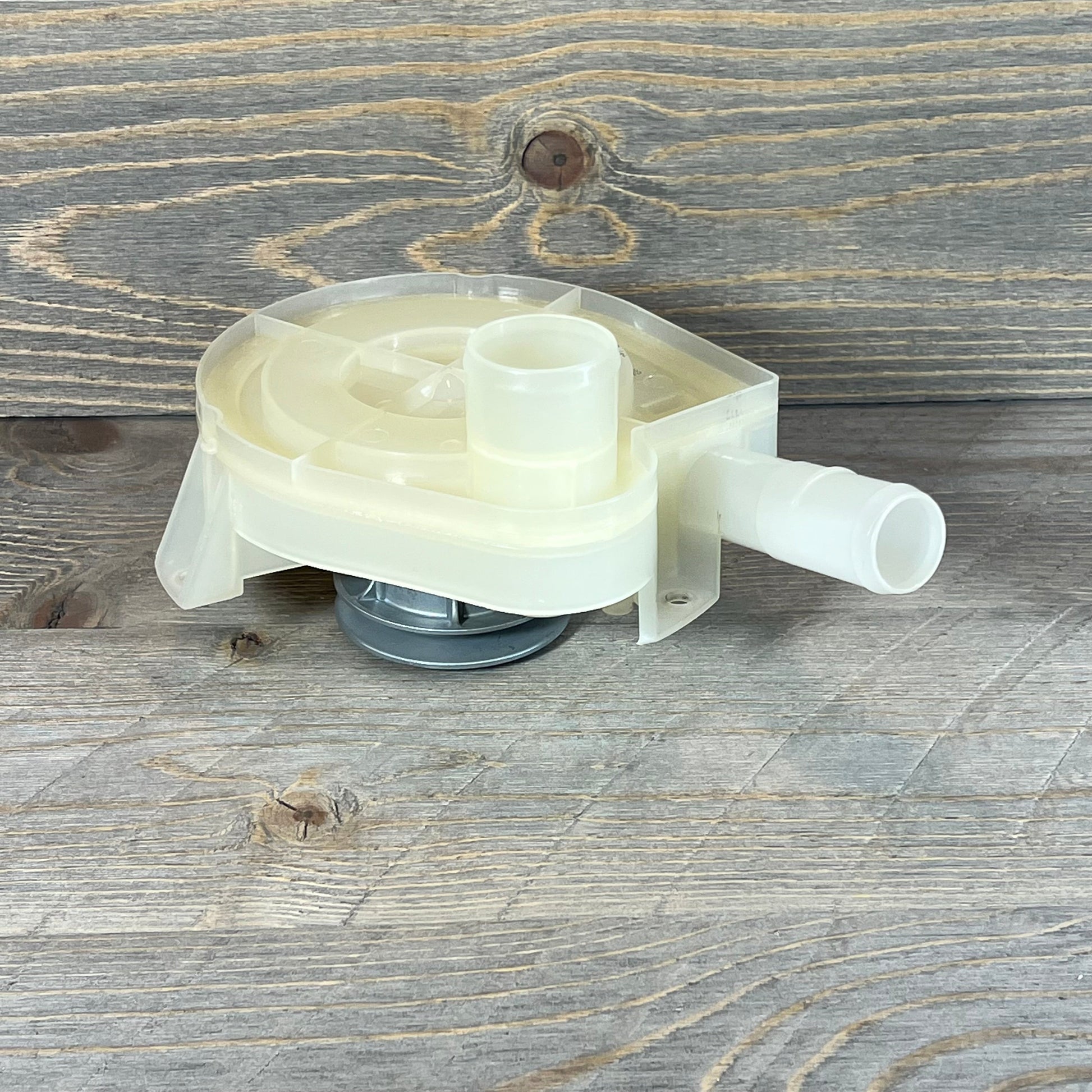 Top load washer drain pump and pulley replacement on a rustic wooden surface, showcasing detailed design and functionality.