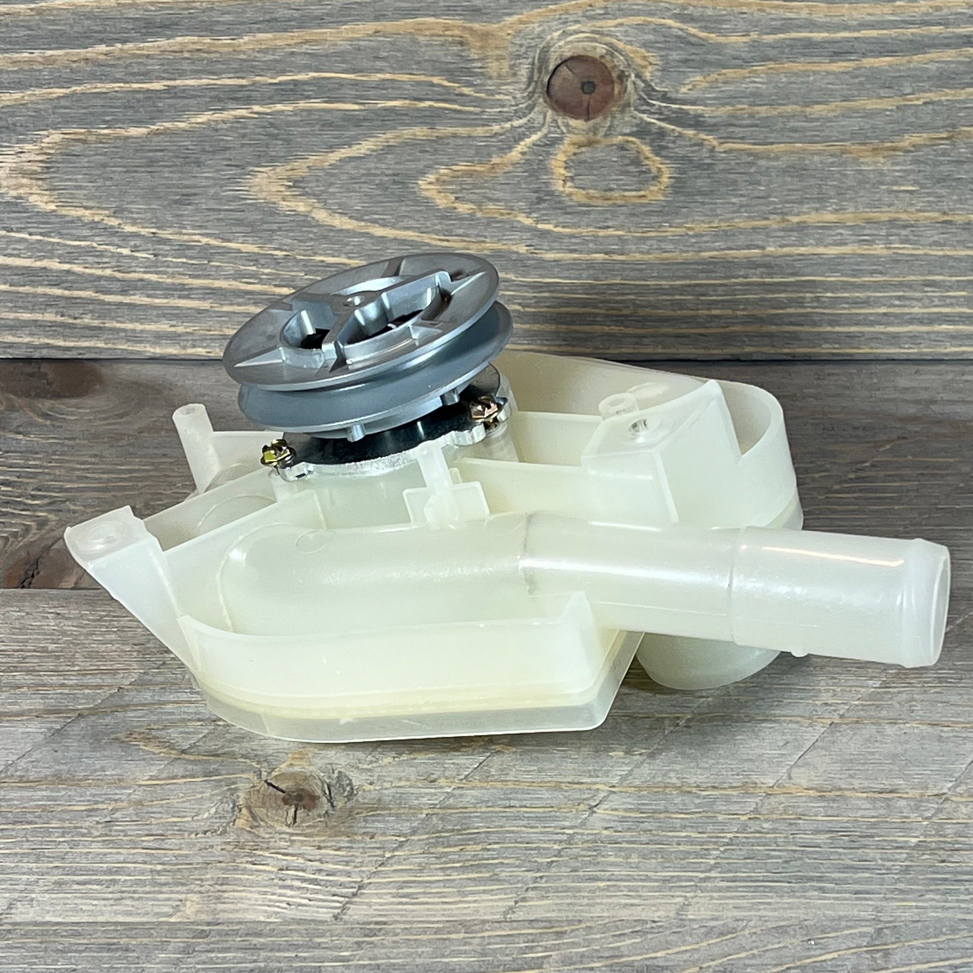 Top load washer drain pump with pulley replacement, featuring durable plastic construction on a rustic wood background.