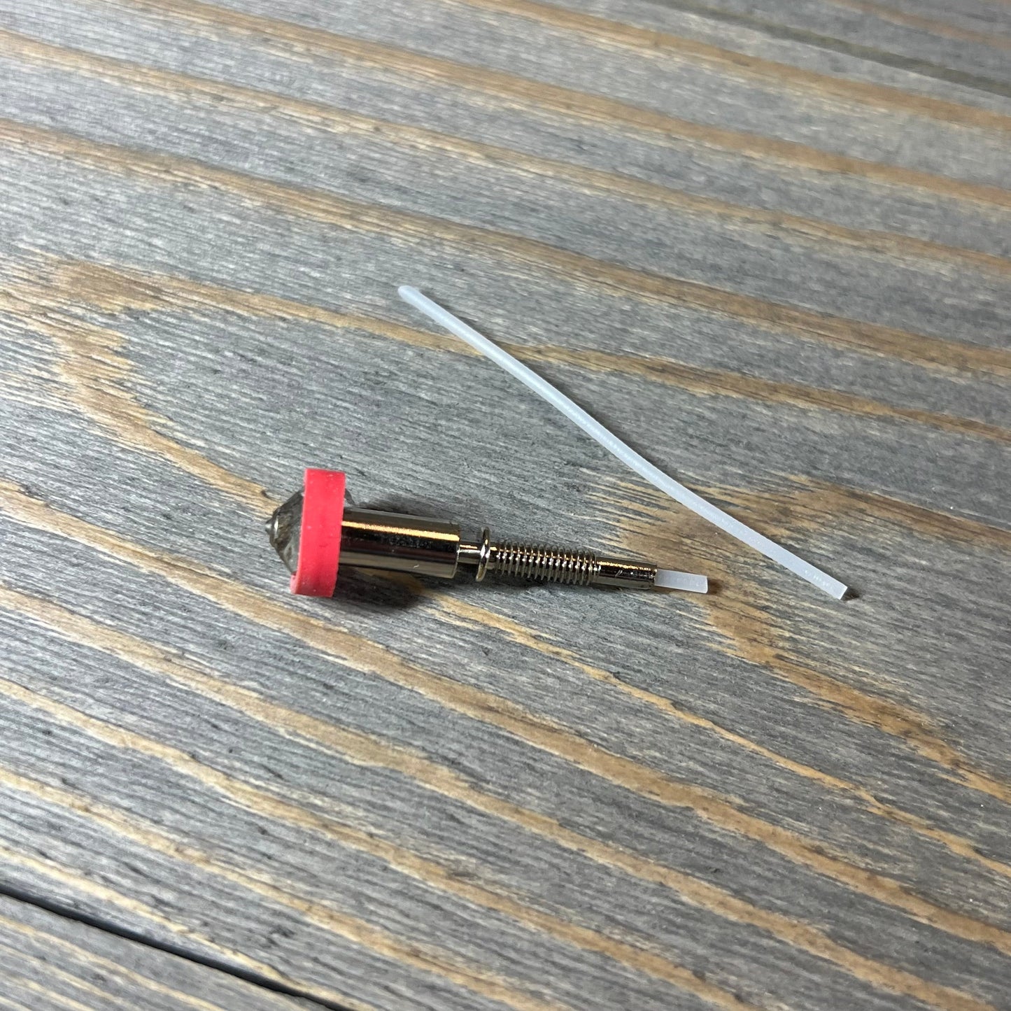 Tungsten carbide nozzle 0.4mm for E3D Revo HotEnd on wooden surface, showcasing high thermal conductivity.