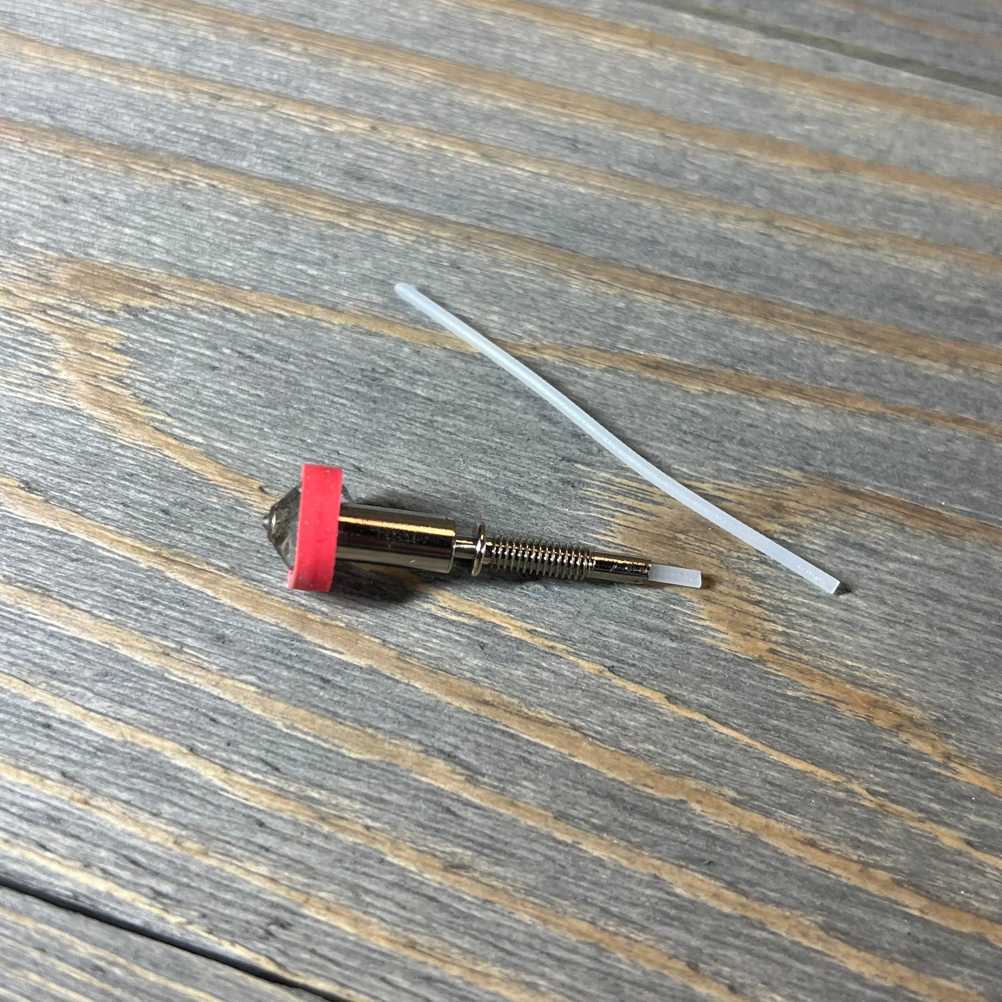 Tungsten carbide nozzle 0.4mm for E3D Revo HotEnd on wooden surface, showcasing high thermal conductivity.