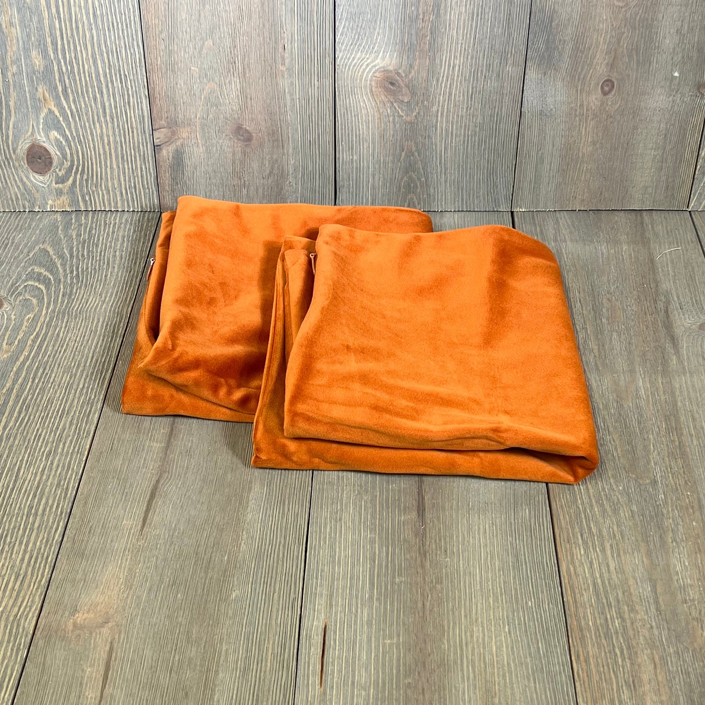 Burnt orange velvet pillow covers on wooden surface, perfect for adding warmth to any couch or bed decor, 16x16 inches.