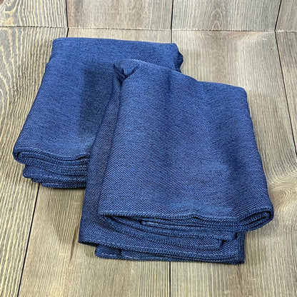 Dark blue waterproof linen pillow covers folded on wooden surface, perfect for outdoor patio furniture and modern living rooms.