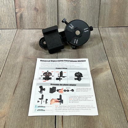 Smartphone scope adapter displayed on wooden surface with assembly instructions, ideal for spotting scopes and telescopes.