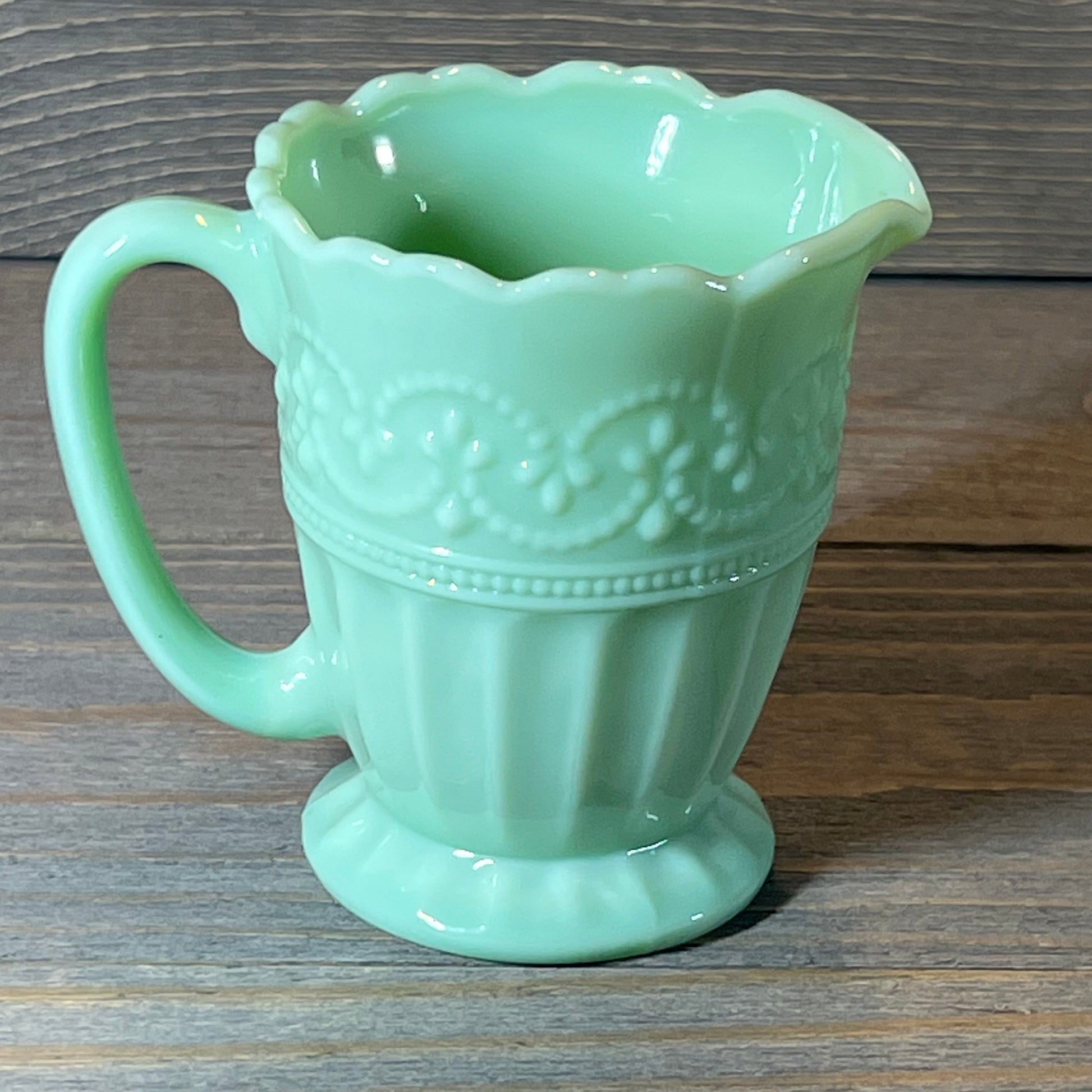 Vintage-inspired jade green creamer with elegant embossed floral design, perfect for adding charm to your table setting.