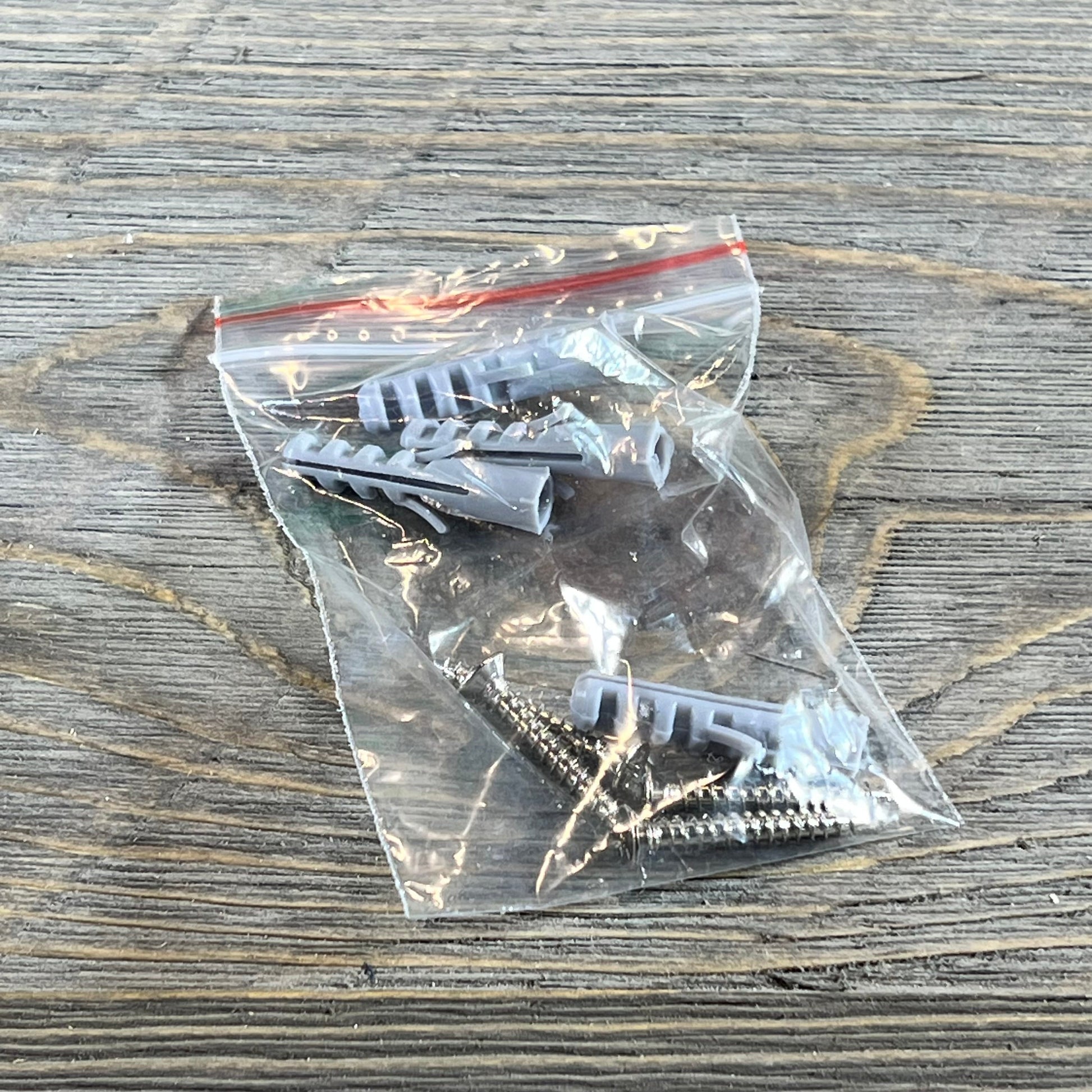 Wall mounting hardware for Play Platoon building brick display shelves in a clear plastic bag on a wooden surface.