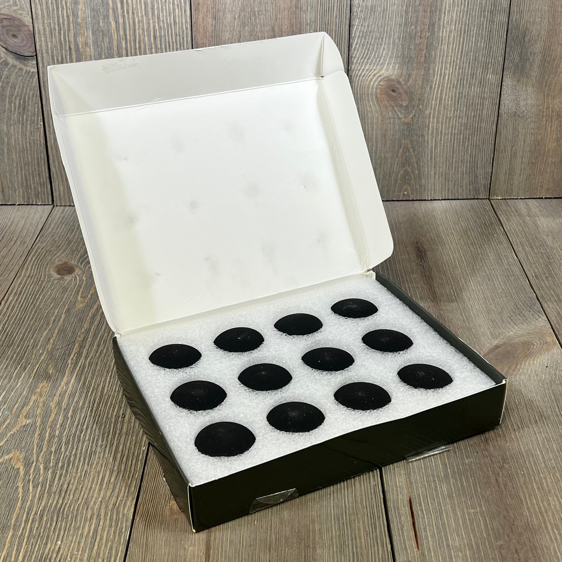 Open box of 12 black magnetic silicone curtain weights for outdoor and bathroom use, featuring a protective foam insert.
