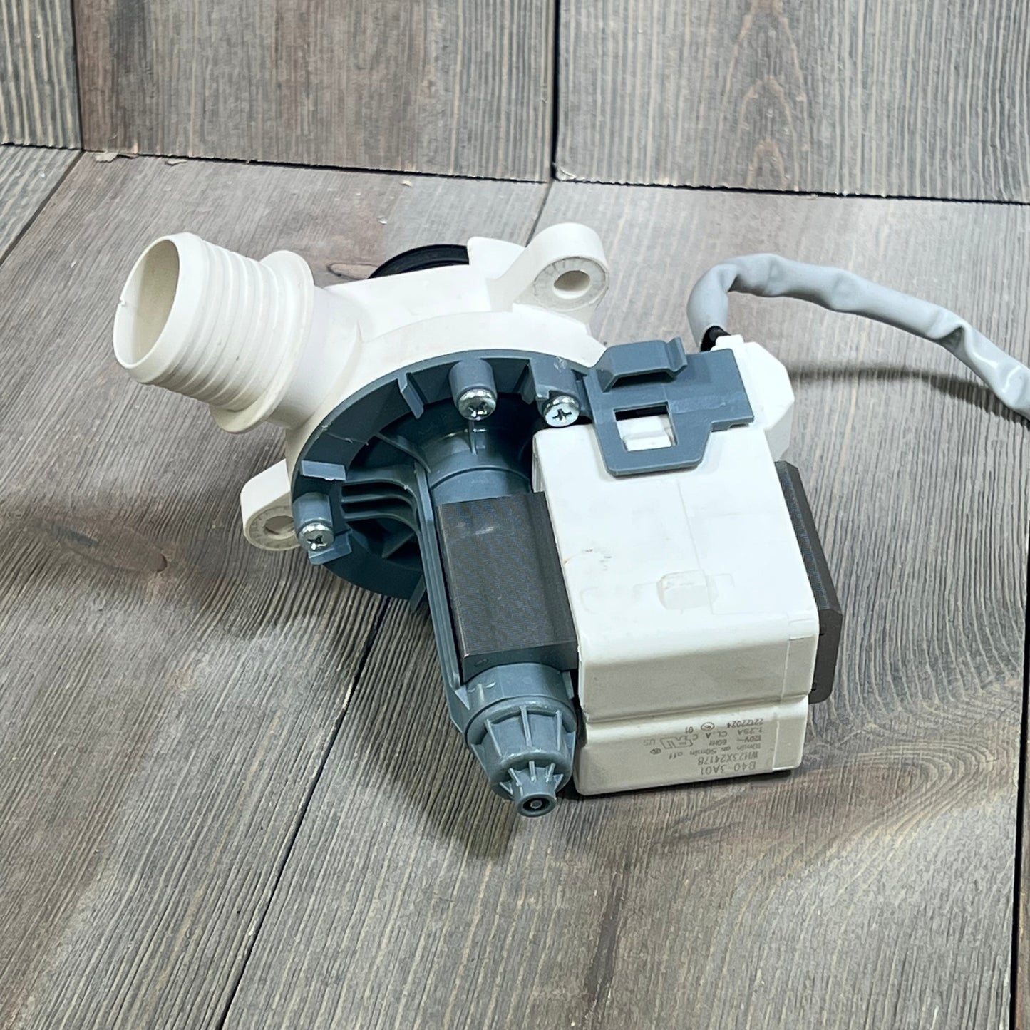 Washer drain pump motor WH23X28418, compatible with Hotpoint GE, shown on wooden surface.