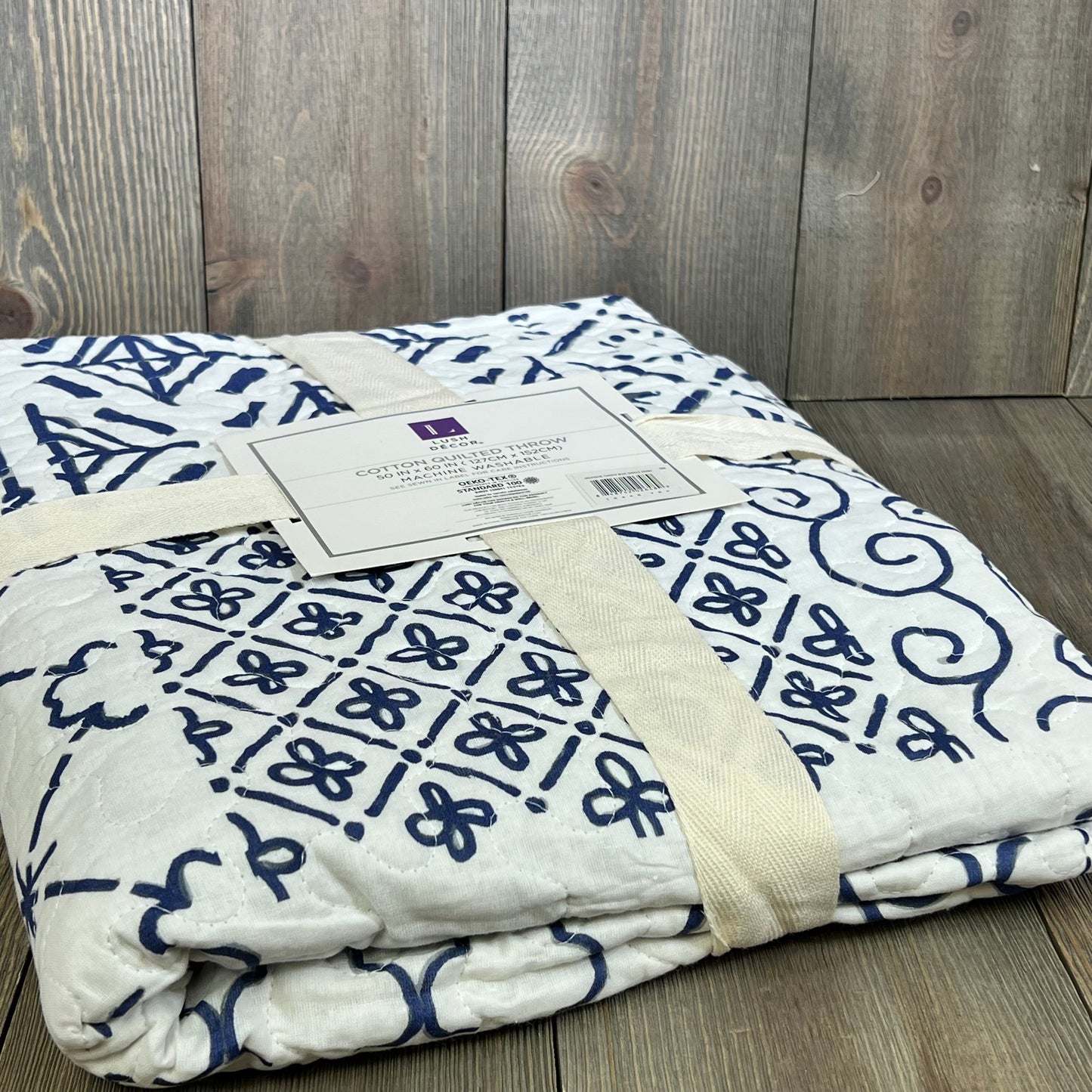 Blue and white patterned Lush Decor Monique Throw, 50x60-inch, neatly folded on a wooden surface.