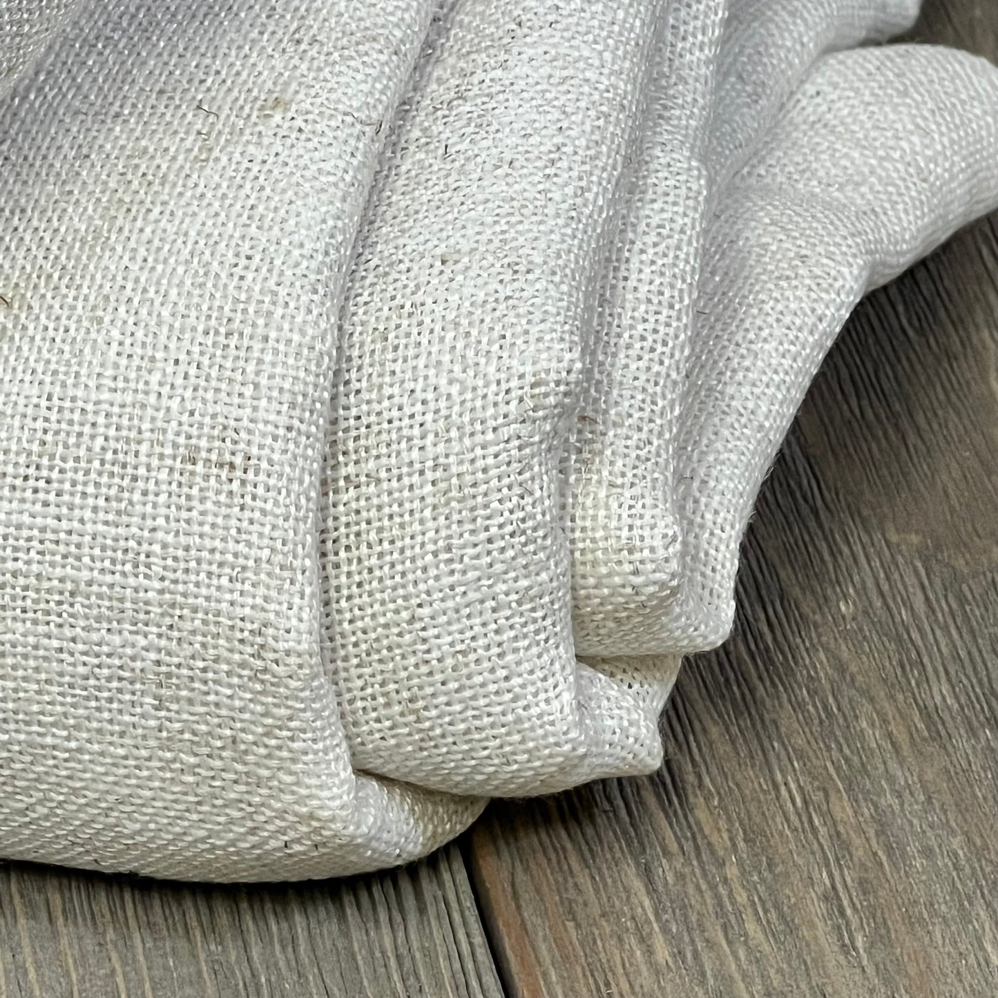 Natural linen texture of NICETOWN curtains, semi-sheer and light filtering, folded on wooden surface, W52 x L90 inches.