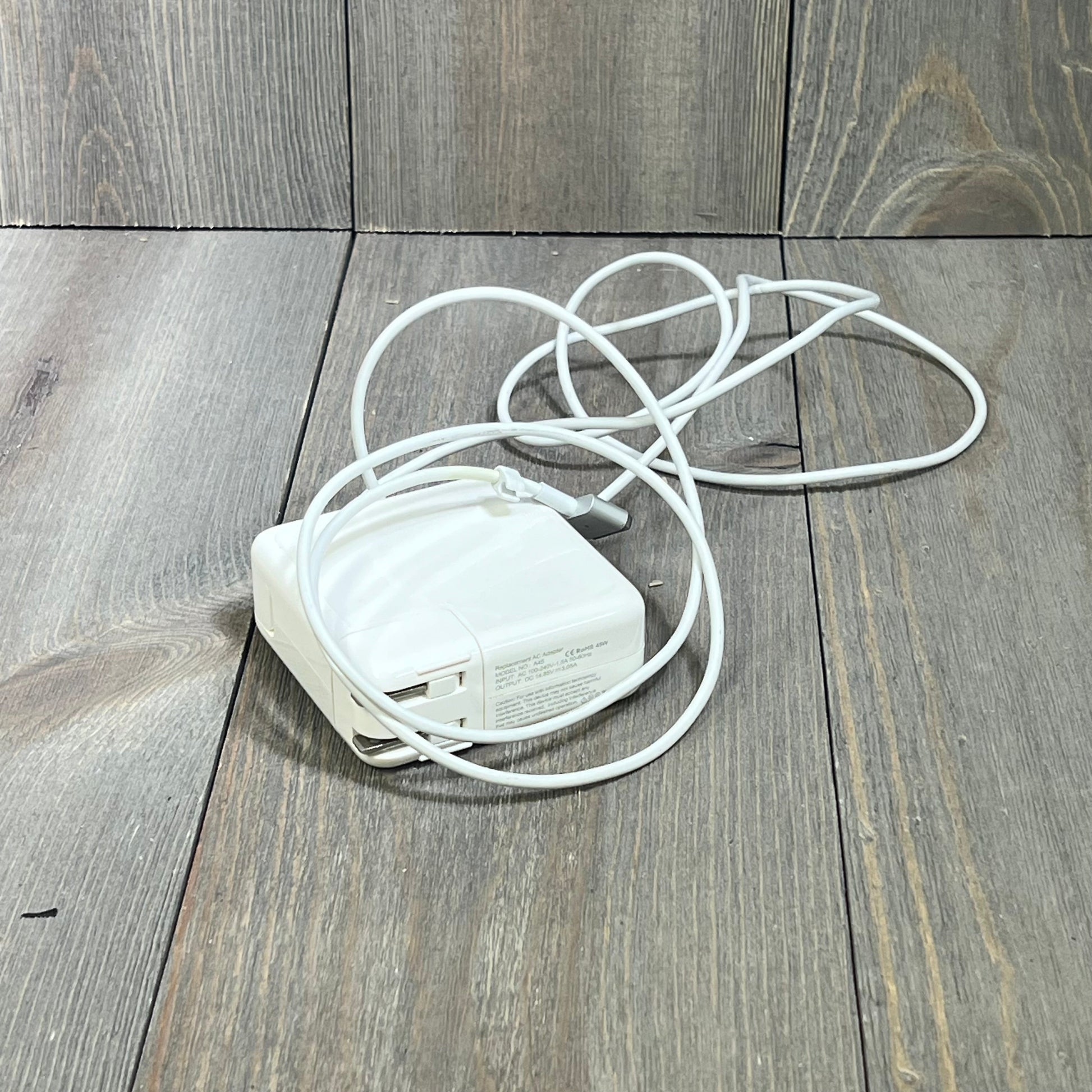 White 45W Mag2 T-Tip MacBook Air charger coiled neatly on a wooden surface, compatible with 11" and 13" models post-2012.
