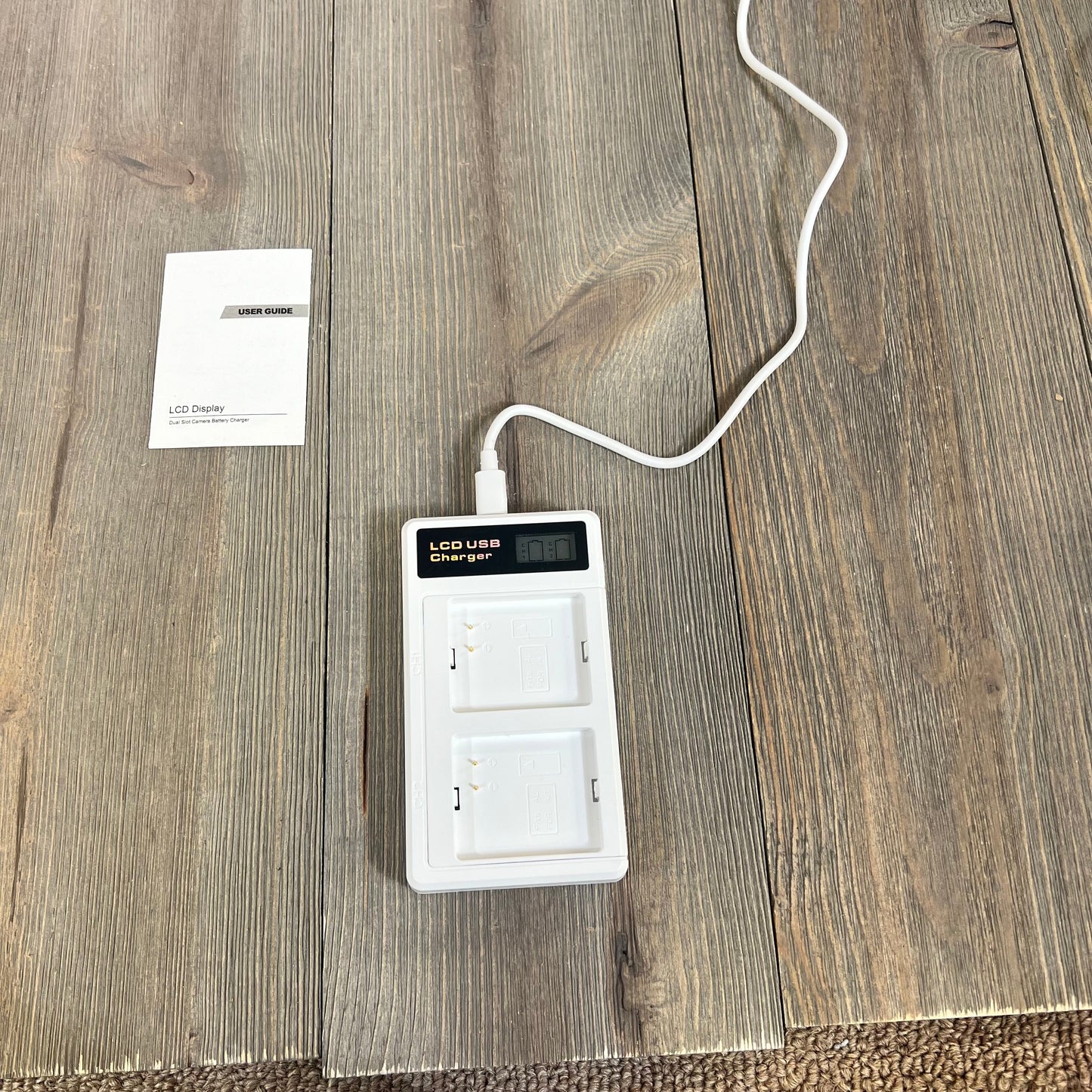 LCD dual charger for Arlo Pro batteries with USB-C cable on wooden surface, includes user guide.