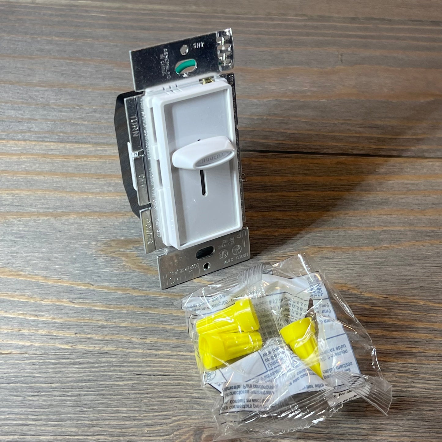 White Lutron Skylark fan control with installation accessories on wooden surface.